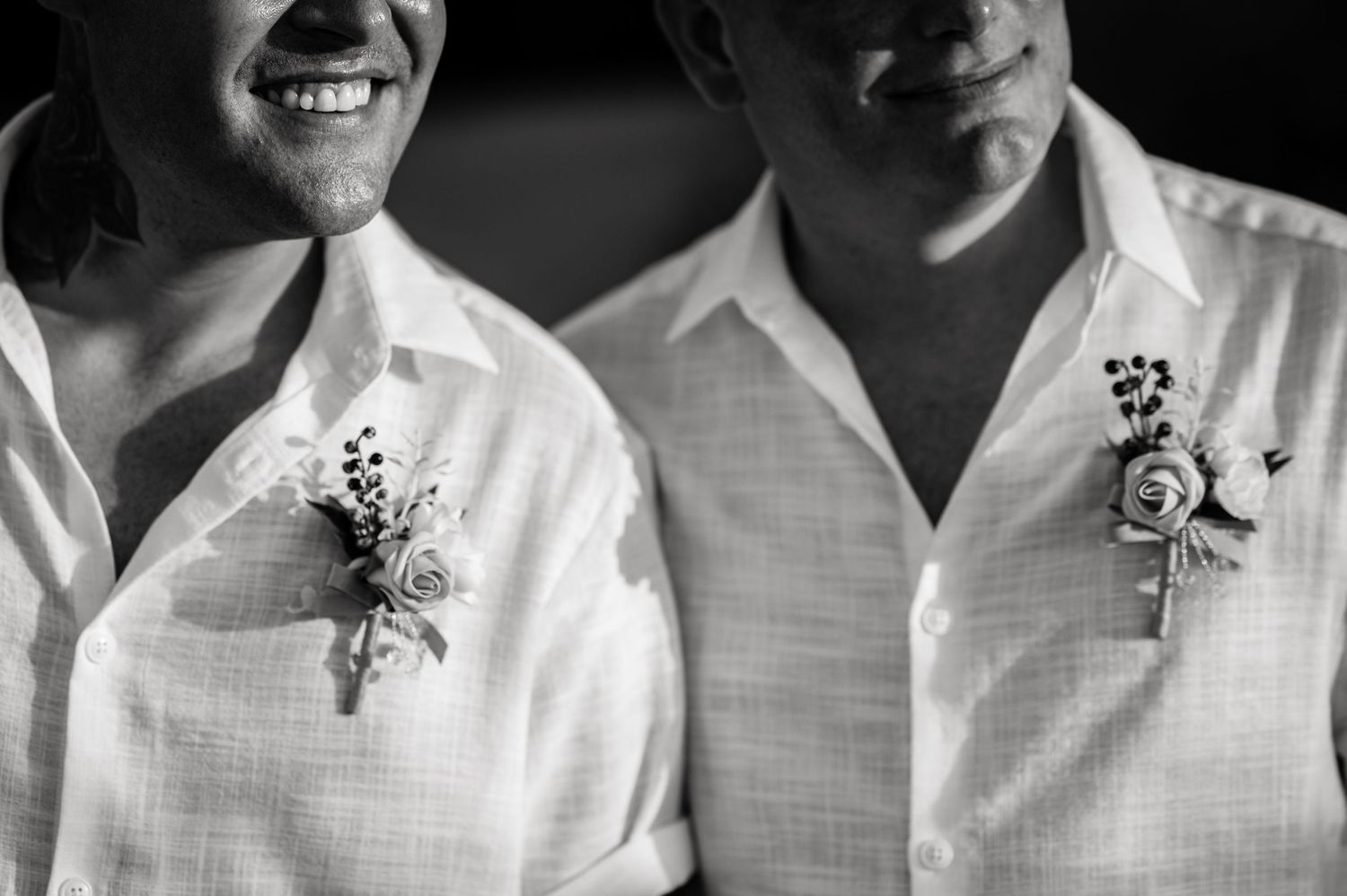Close-up of matching floral boutonnieres on white dress shirts.