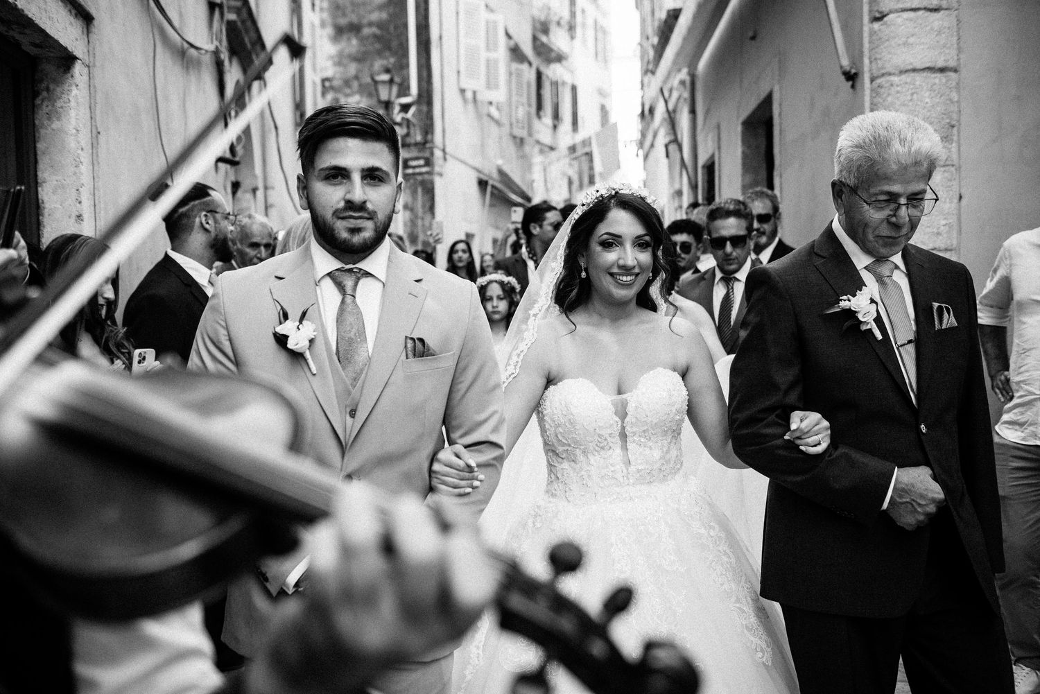 Wedding celebration in a narrow European street with guests walking and celebrating.