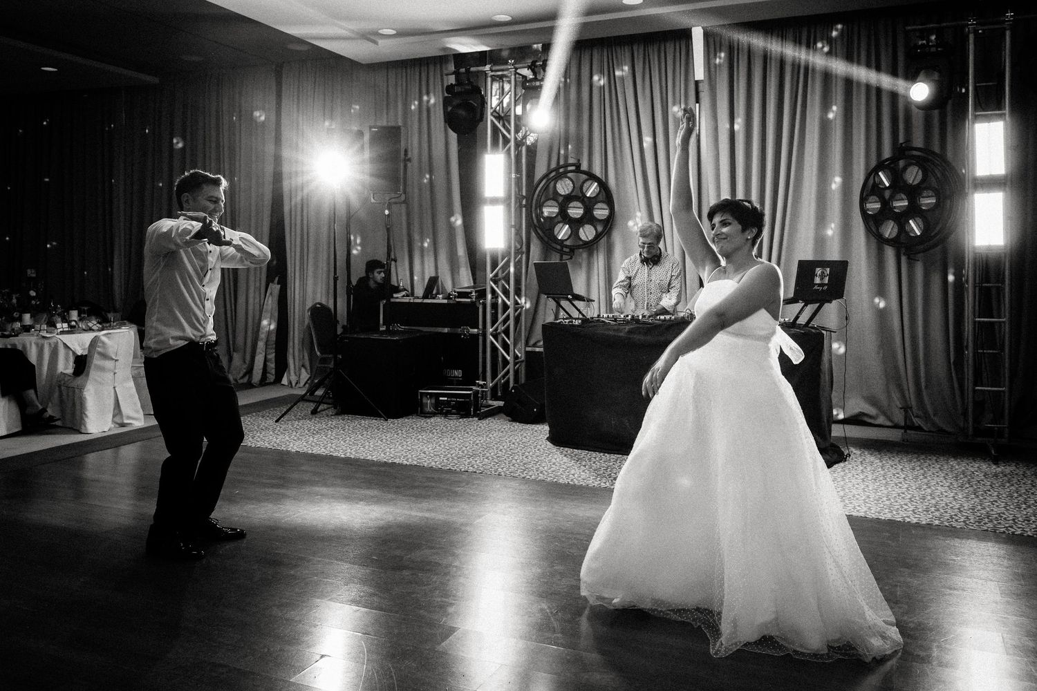 A couple shares a romantic dance on an elegant ballroom floor with dramatic lighting.
