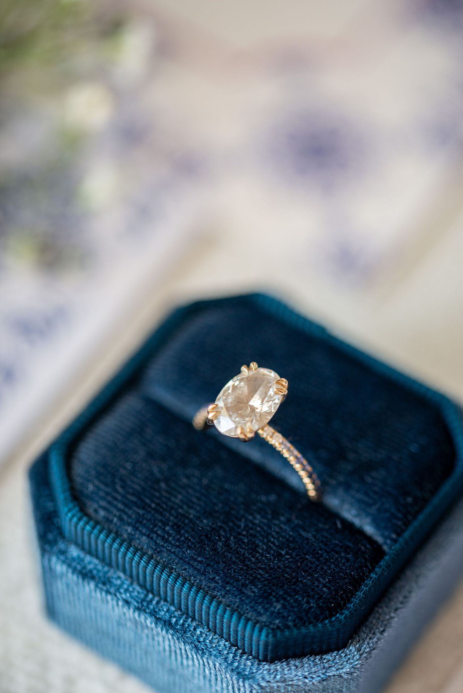 A sparkling diamond engagement ring sits elegantly on a navy blue velvet ring box.