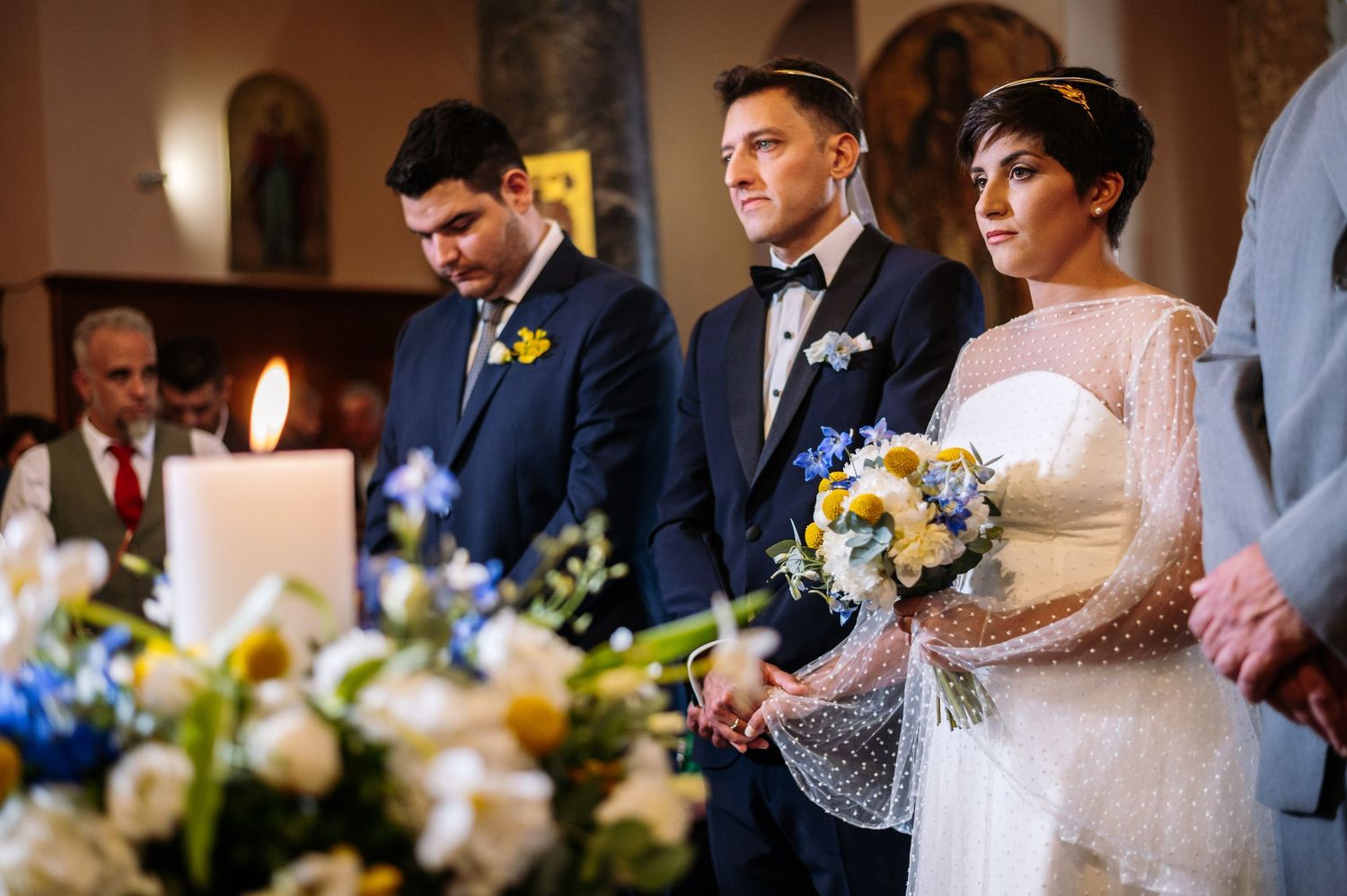 Close-up of wedding ceremony decorations featuring white candles and blue and yellow flower arrangements.