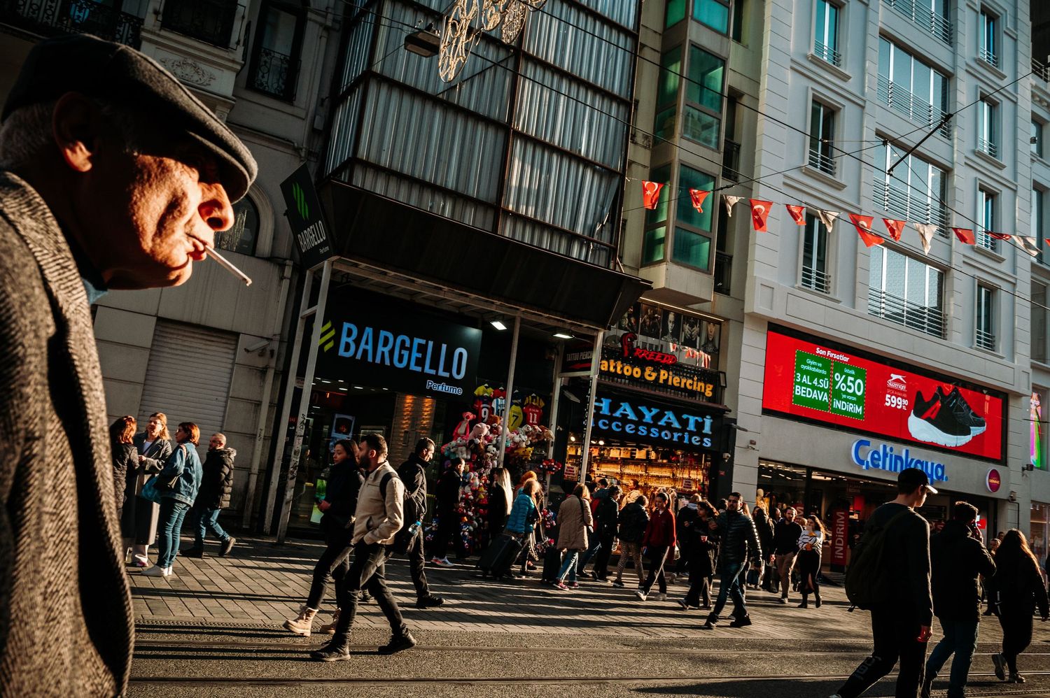 Modern city street with illuminated storefronts and pedestrians walking past shops.
