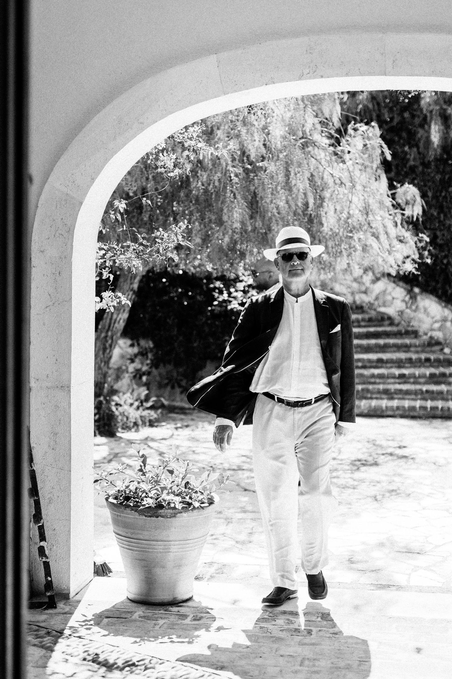 Black and white wedding scene under arched walkway with stone architecture.