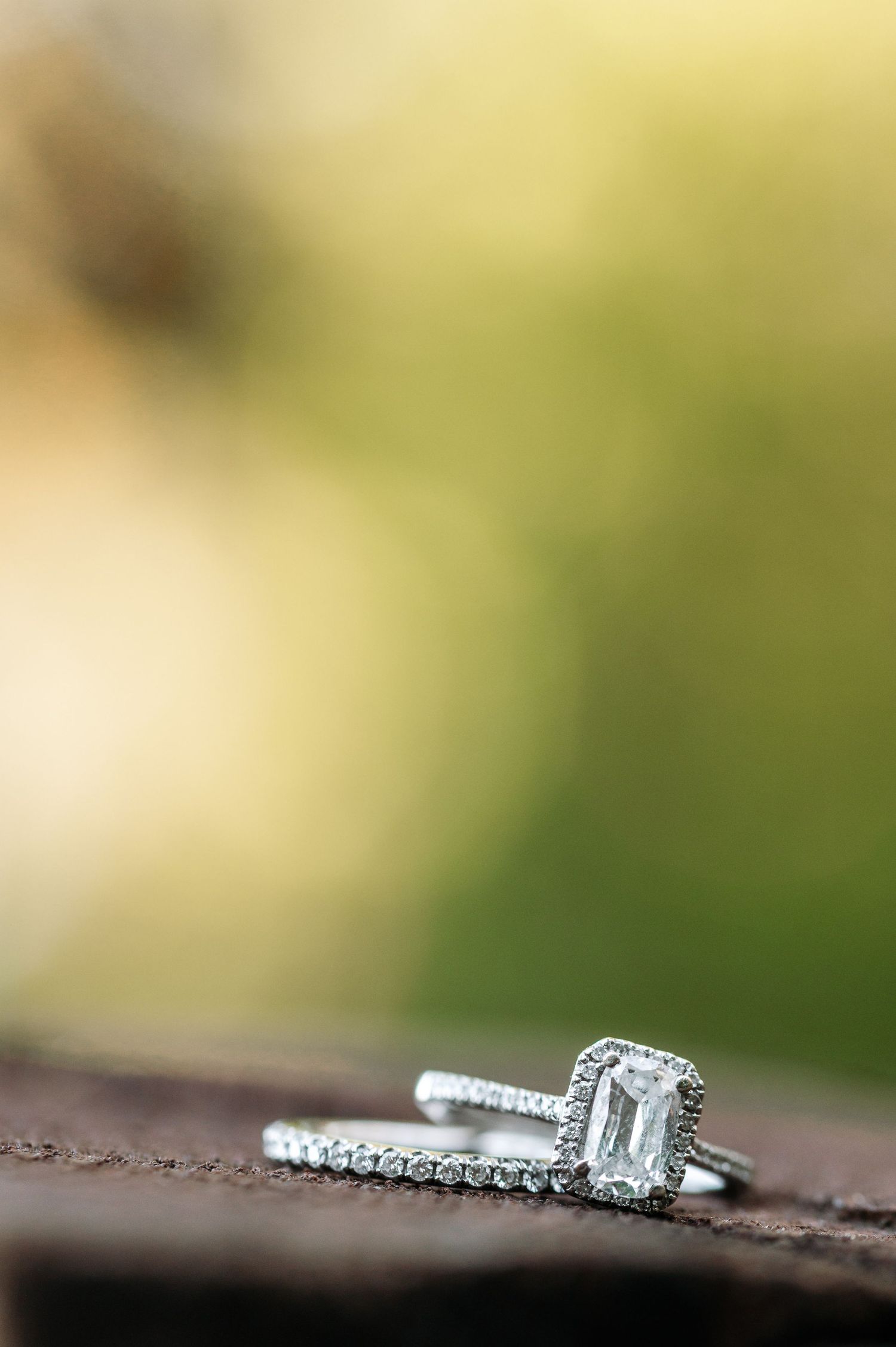 Close-up of an elegant diamond engagement ring and wedding band on a wooden surface.