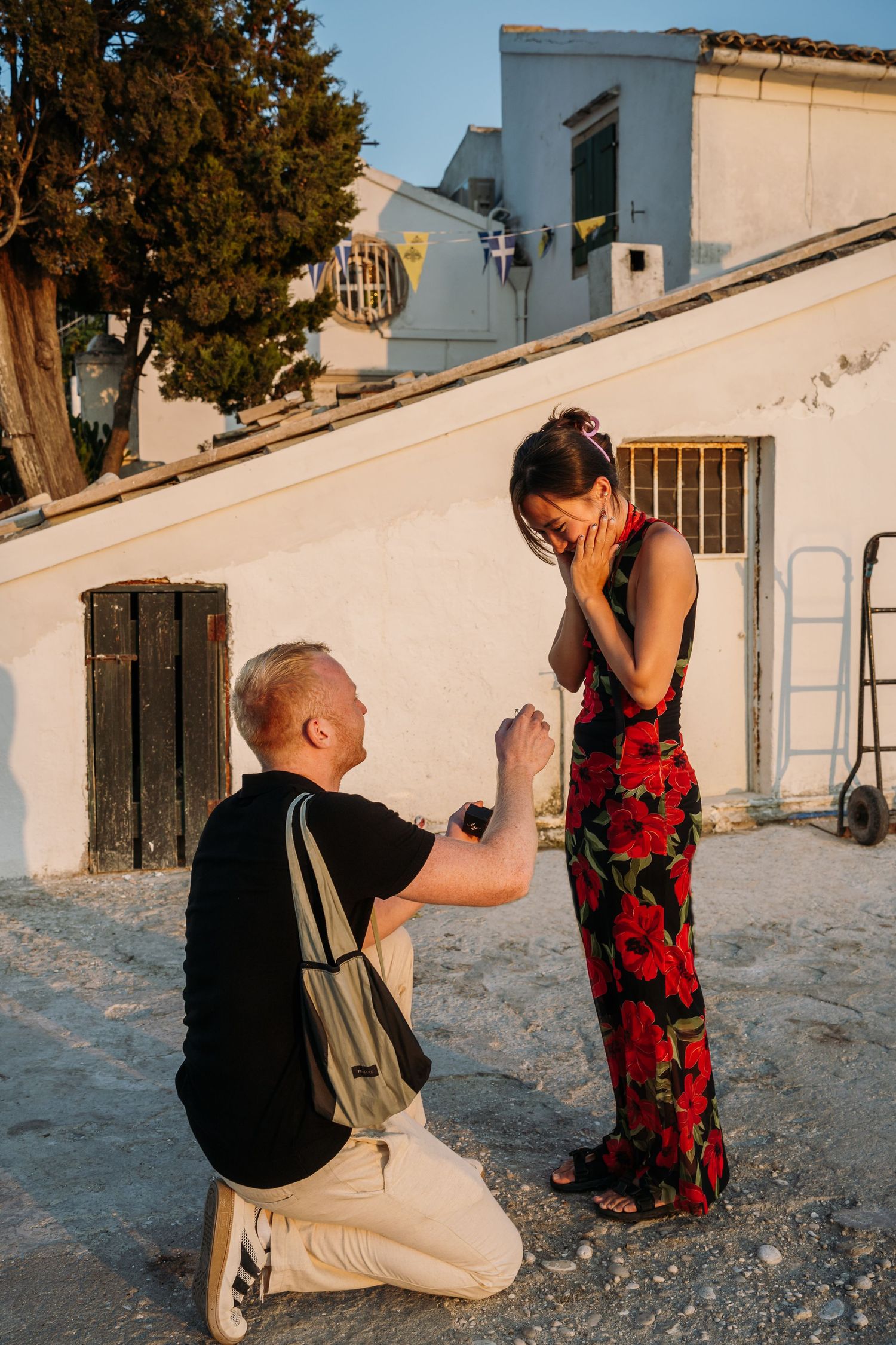 A surprise proposal moment captured at sunset against white Mediterranean architecture.