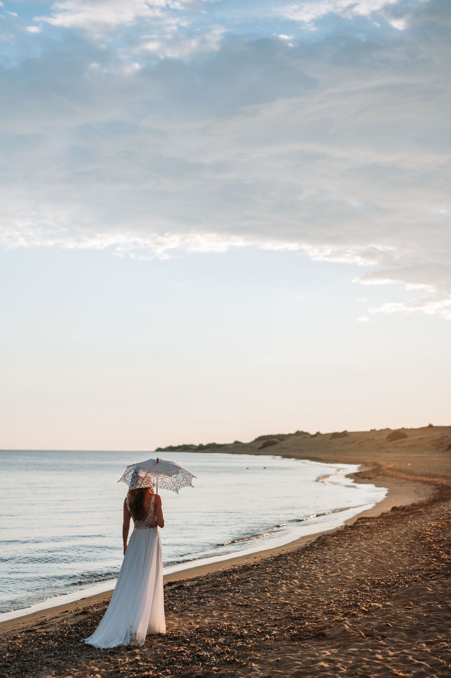 Scenic coastal wedding photography with dramatic cloudy sky and rocky beach landscape.