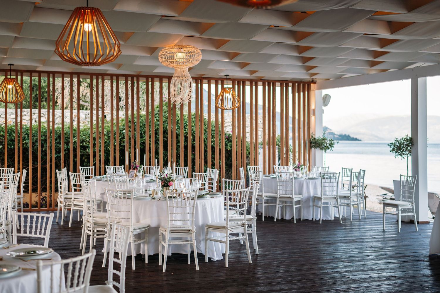 Modern reception hall with hanging pendant lights and white table settings.