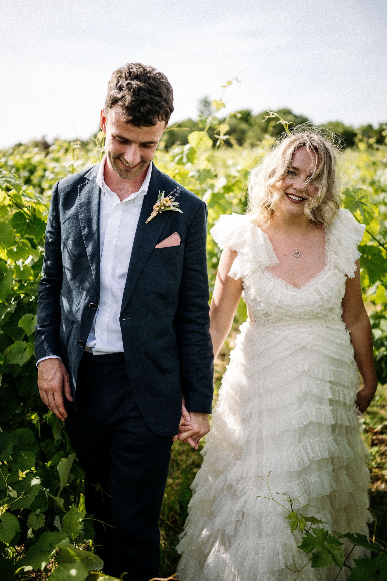 Candid moments of newlyweds laughing together in vineyard setting.