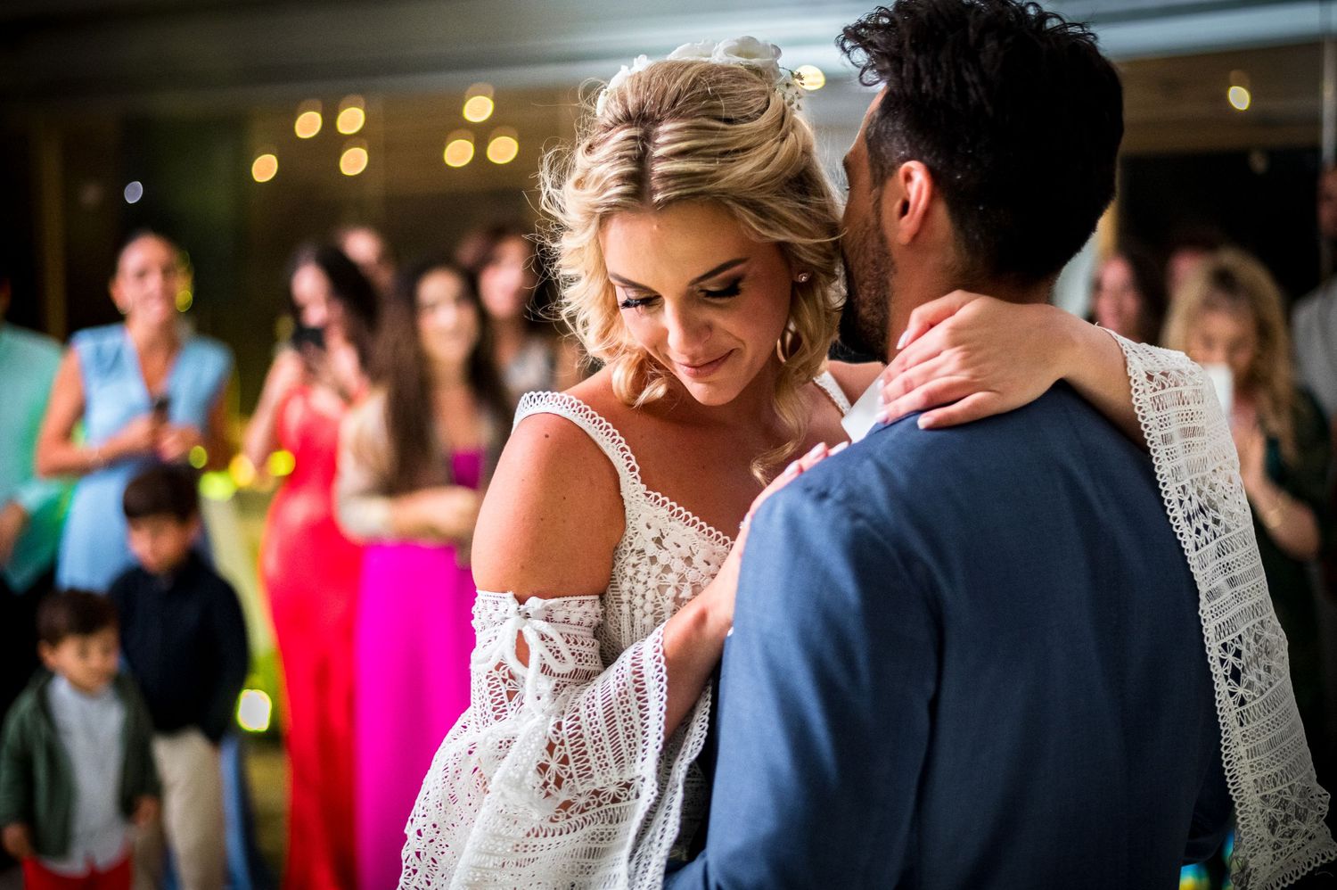 Newlyweds dance surrounded by guests at evening wedding celebration.