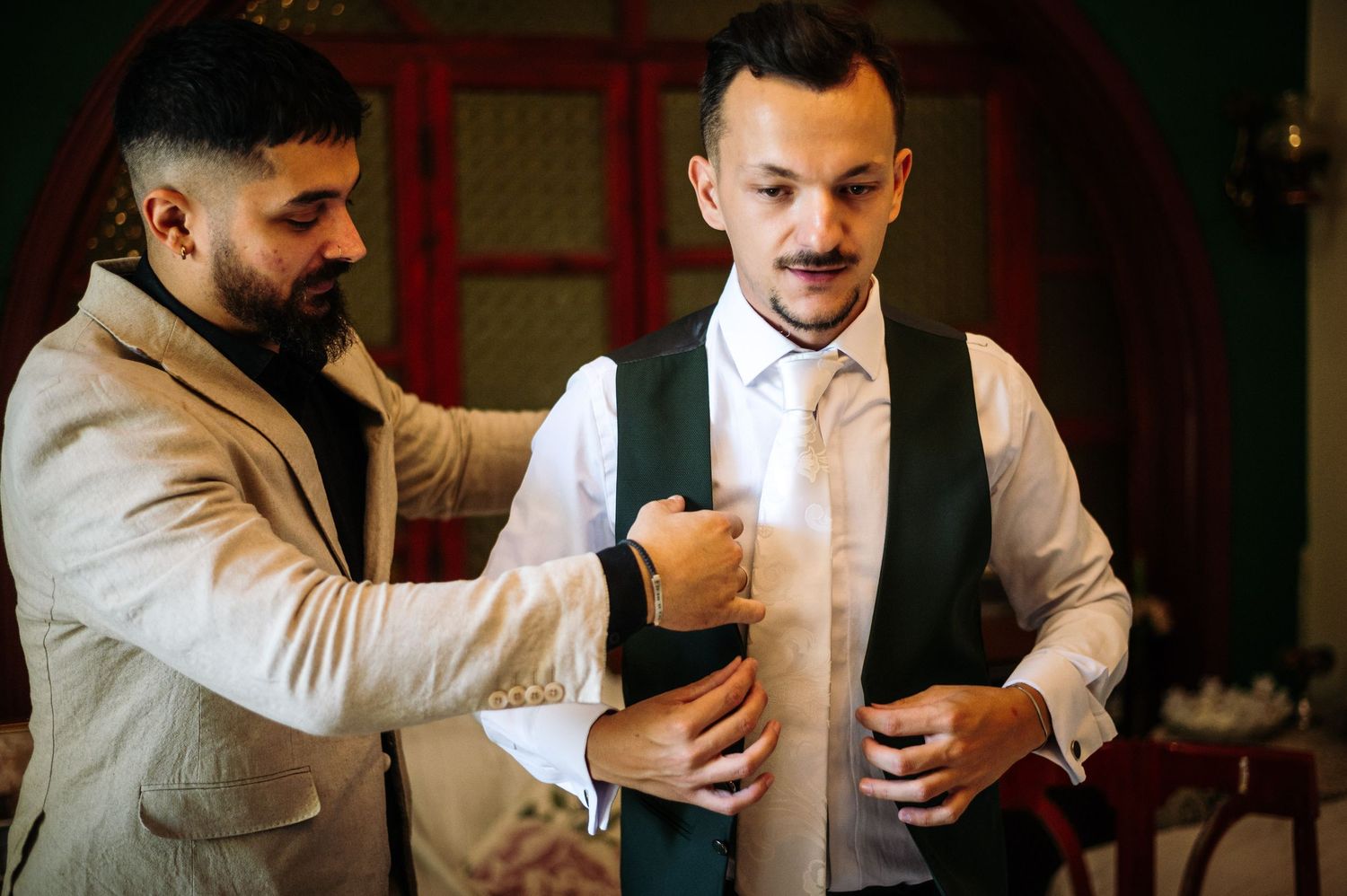 Men in white shirts and vests sharing drinks at a formal gathering.
