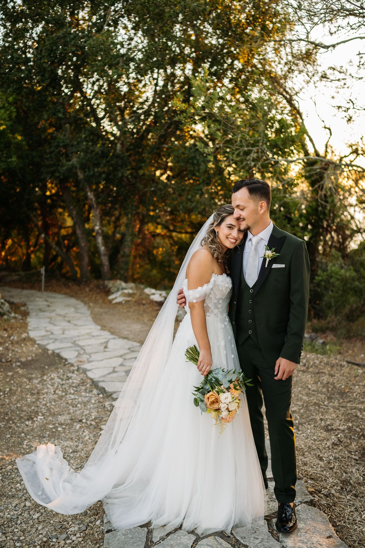 Romantic wedding portraits of couple walking together on a rustic path surrounded by autumn trees.