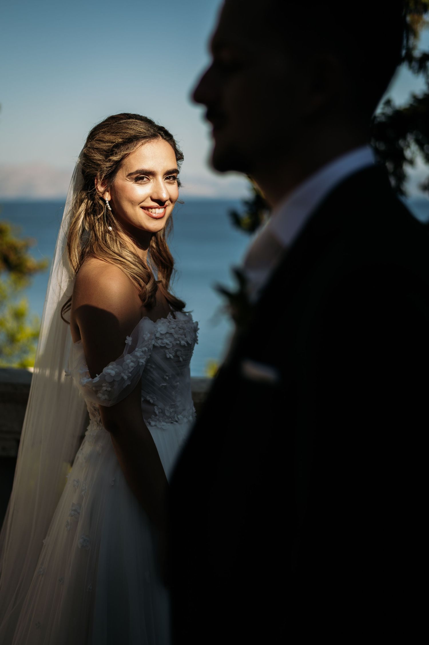 Artistic silhouette portrait against blue sky with ocean backdrop.