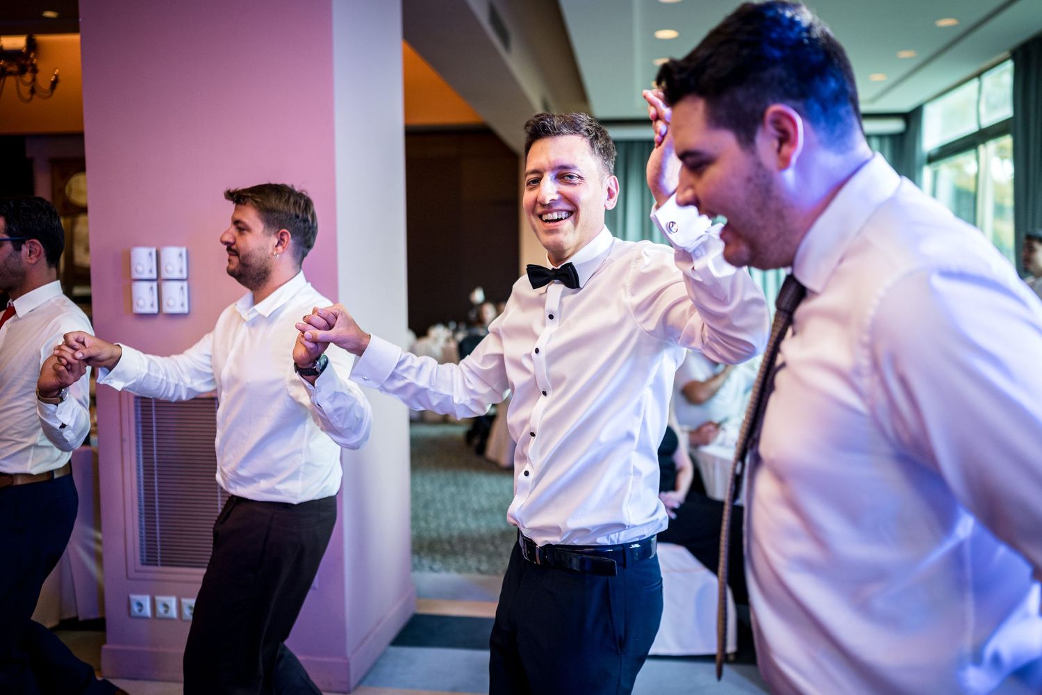 Groomsmen in white shirts preparing for wedding festivities in a modern venue.