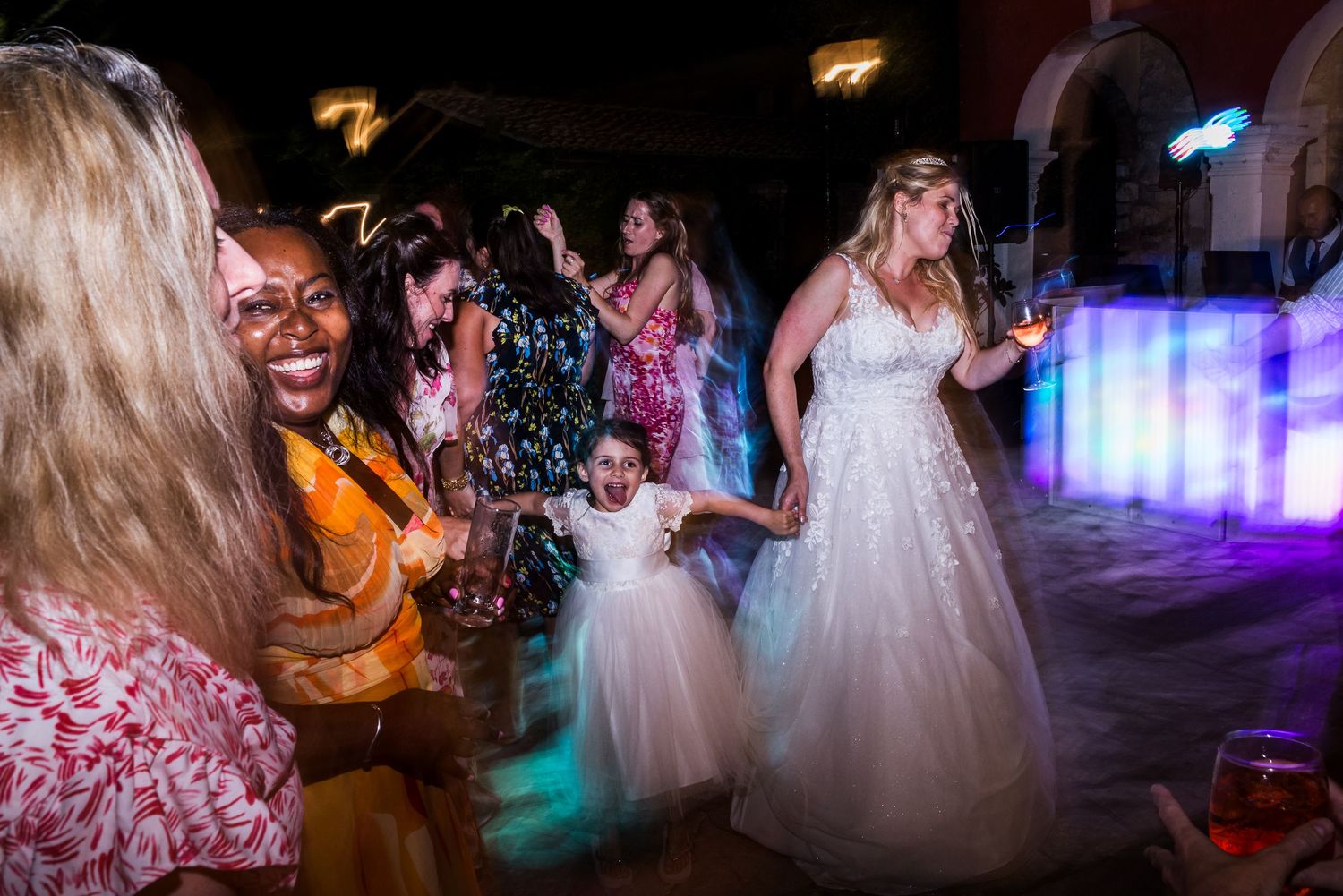 Guests dancing and celebrating at a wedding reception under atmospheric lighting and disco effects.