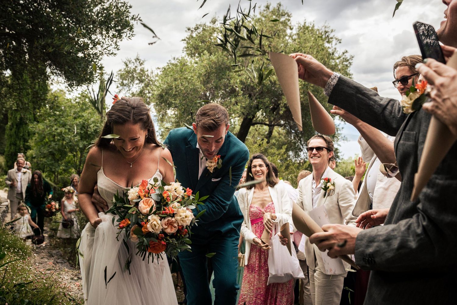 Wedding guests celebrating and cheering during an outdoor garden ceremony.