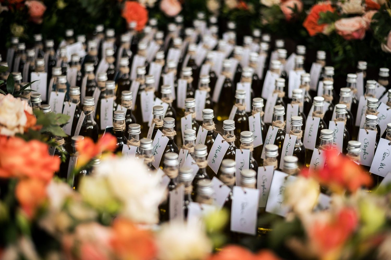 Rows of wine bottles arranged as wedding favors with custom labels.