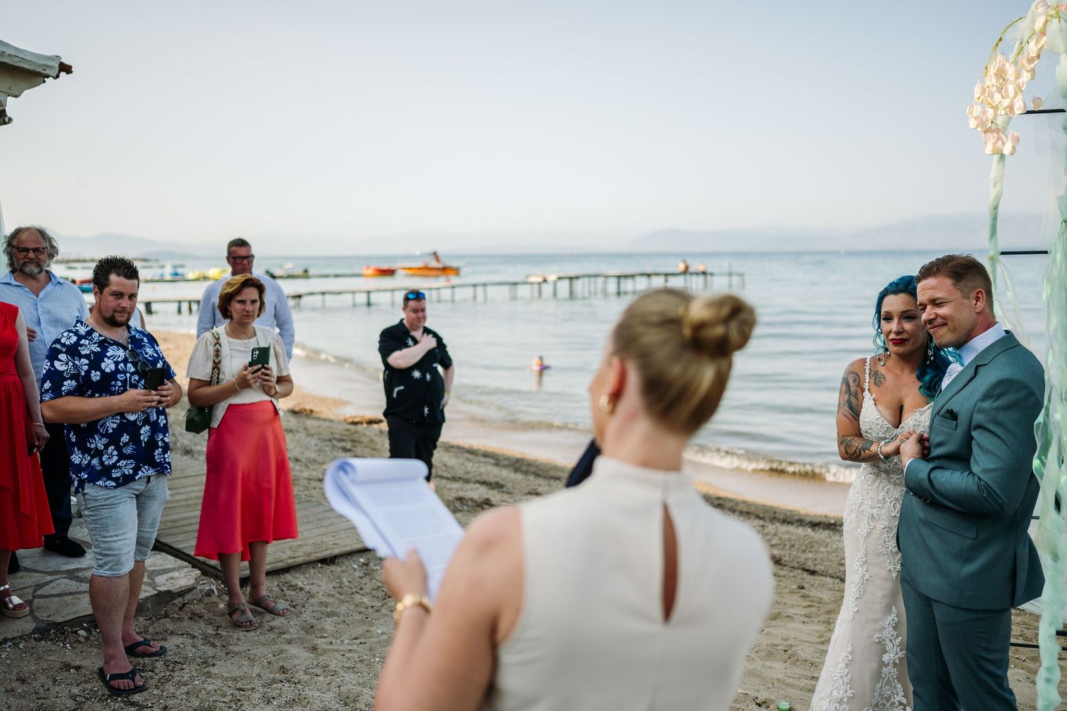 Scenic beach wedding ceremony with guests gathered along the shoreline.
