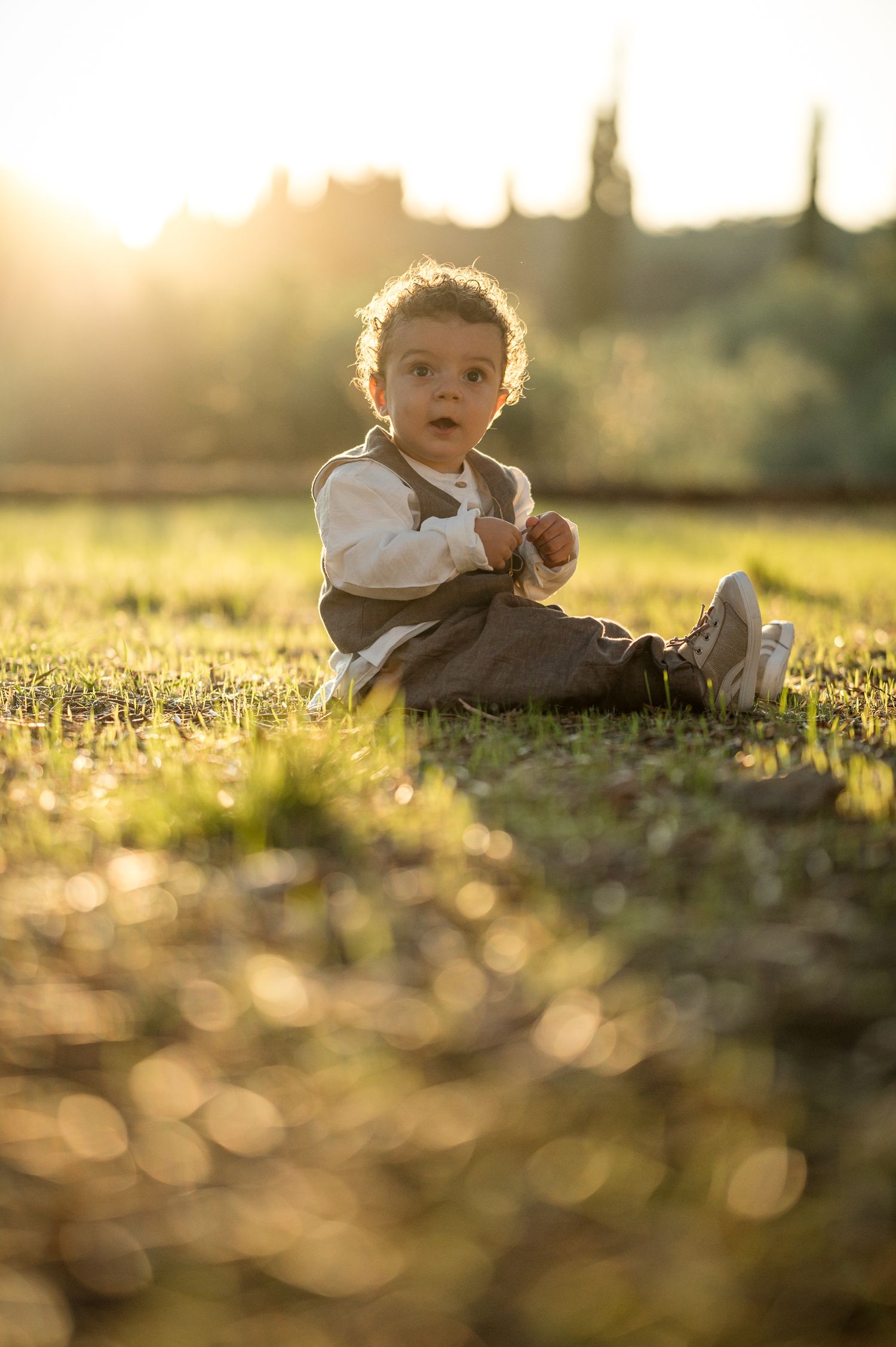 Baby sitting in grass during golden hour with beautiful bokeh lighting effects.