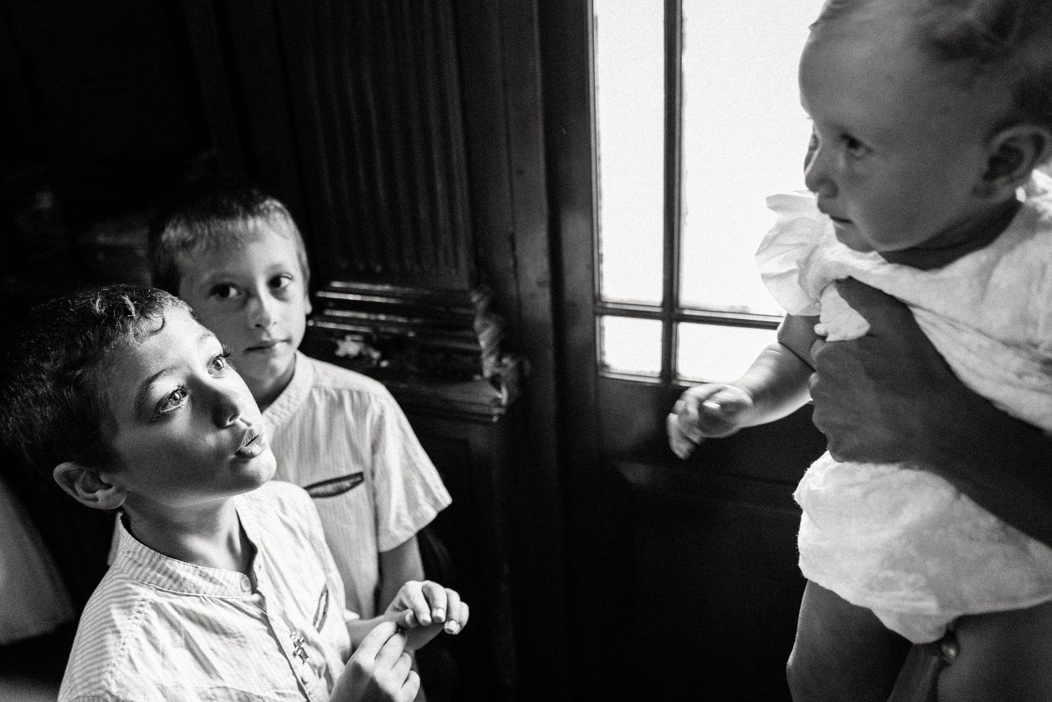 Series of intimate black and white portraits showing interactions during a baptism ceremony.