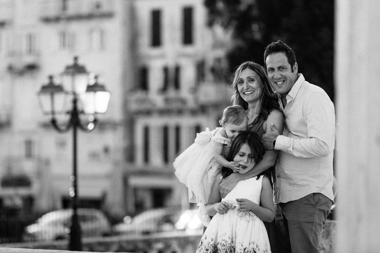 Black and white sequence of joyful moments between family members at an outdoor event.