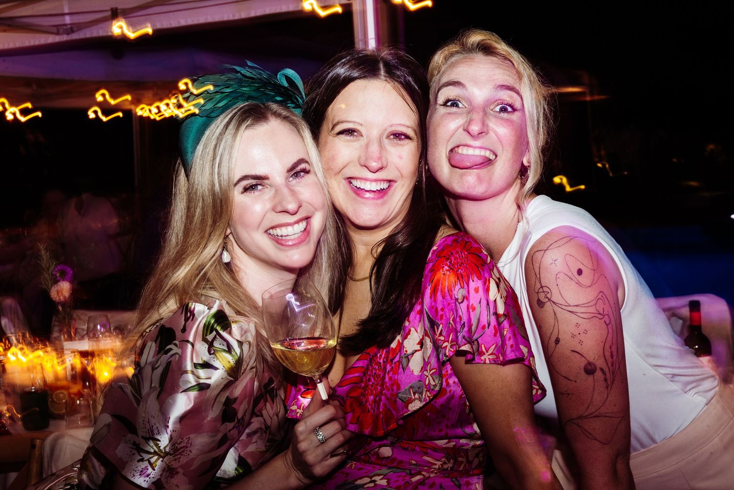 Party guests dancing and celebrating at a nighttime event with colorful lighting and festive atmosphere.