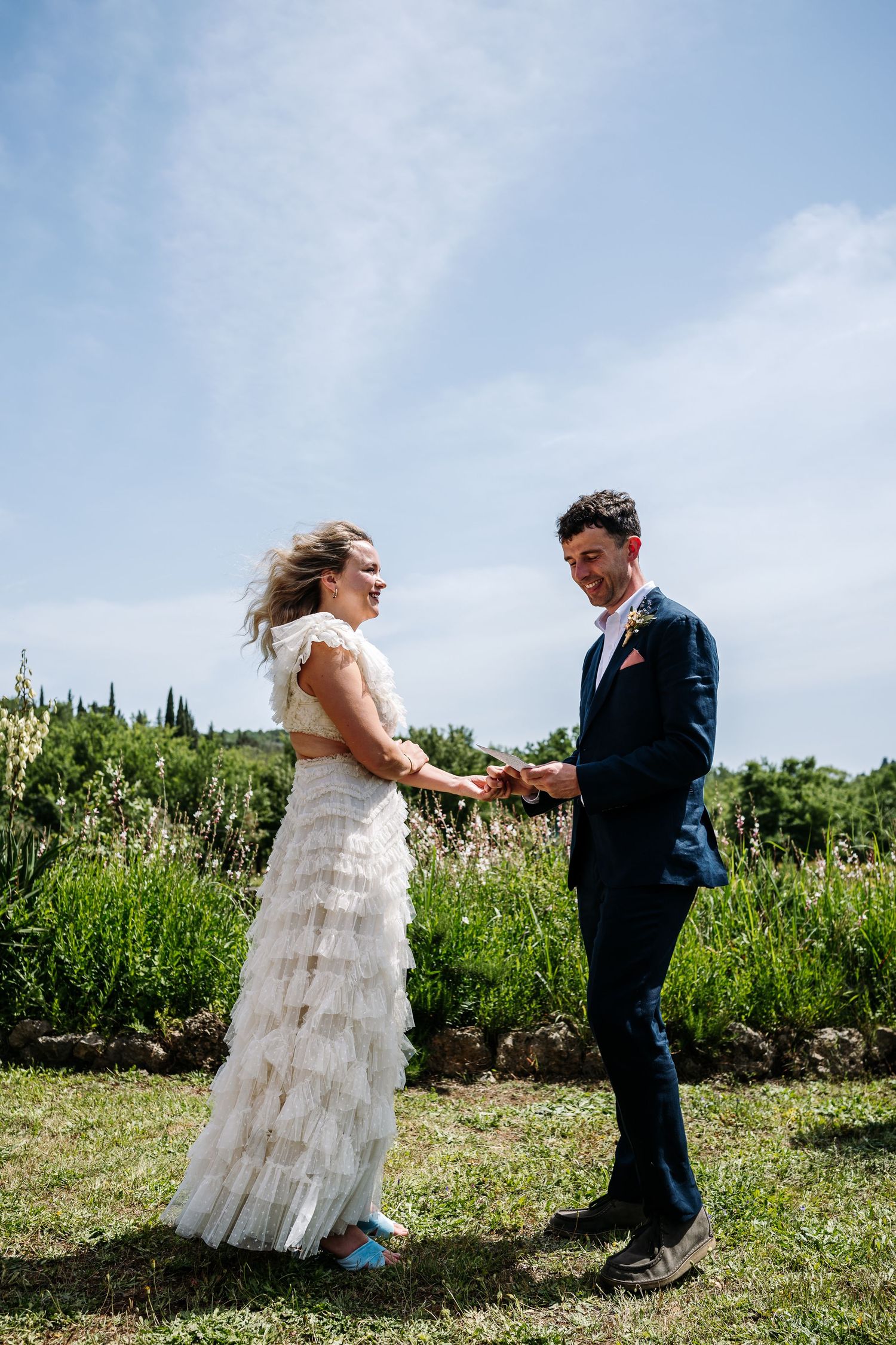 Couple dances together in a sunny field during their wedding celebration.