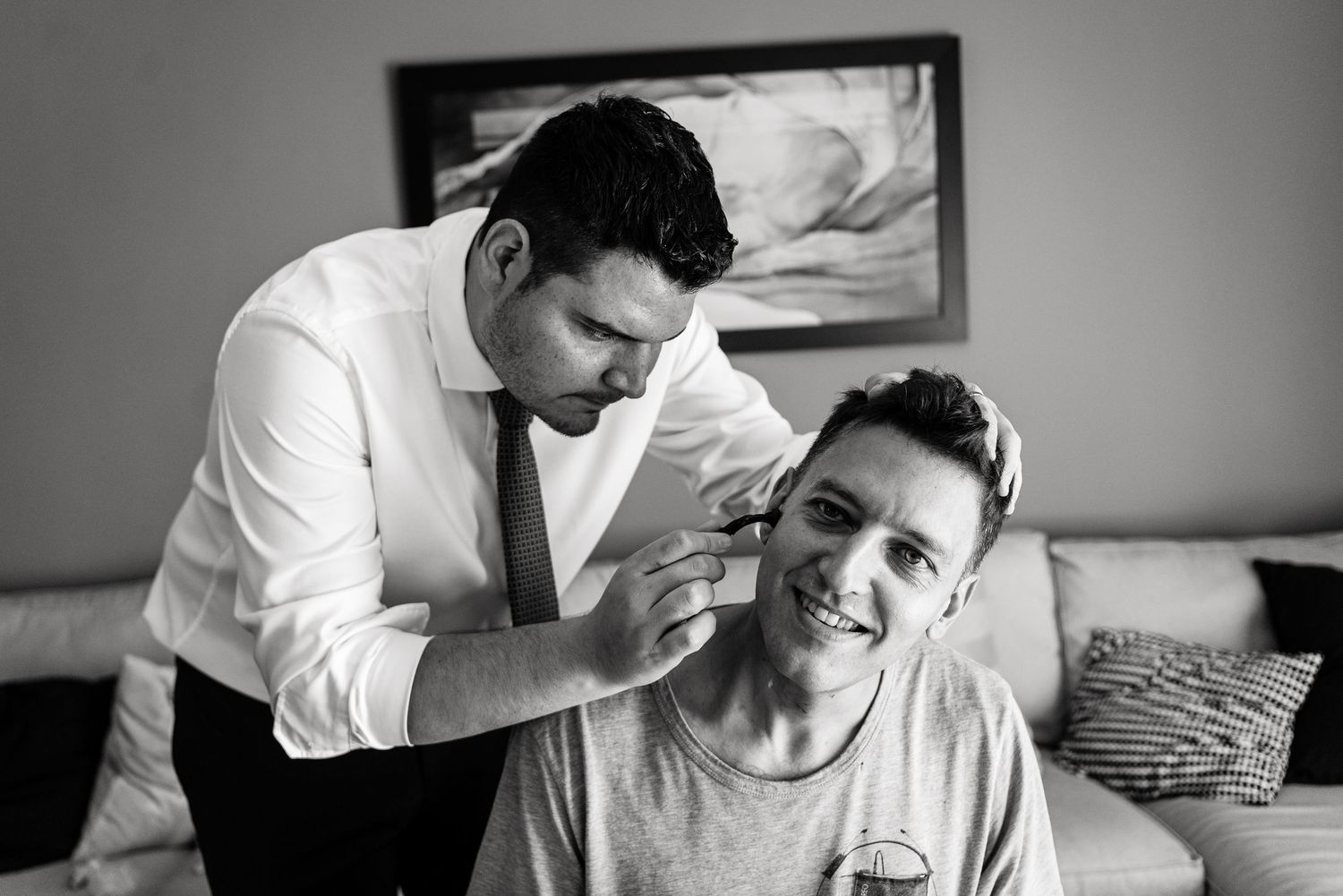 Two people in formal attire getting ready in a room with natural lighting.
