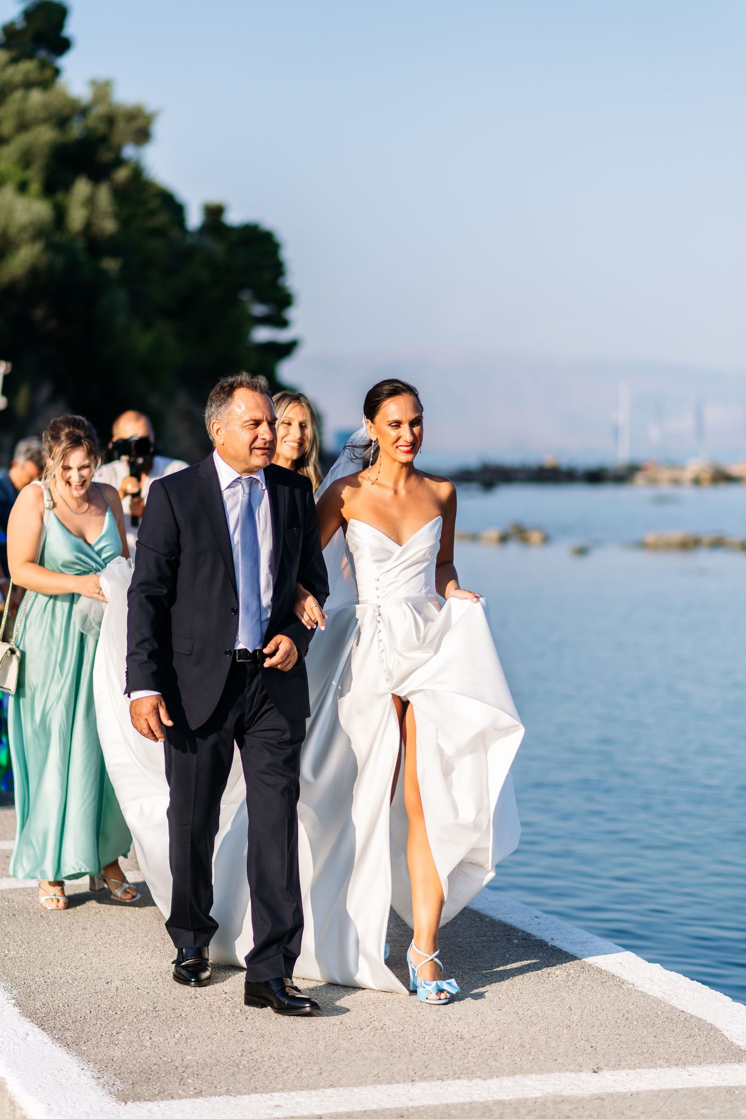 Wedding party poses along a waterfront walkway with bridesmaids in mint green dresses.