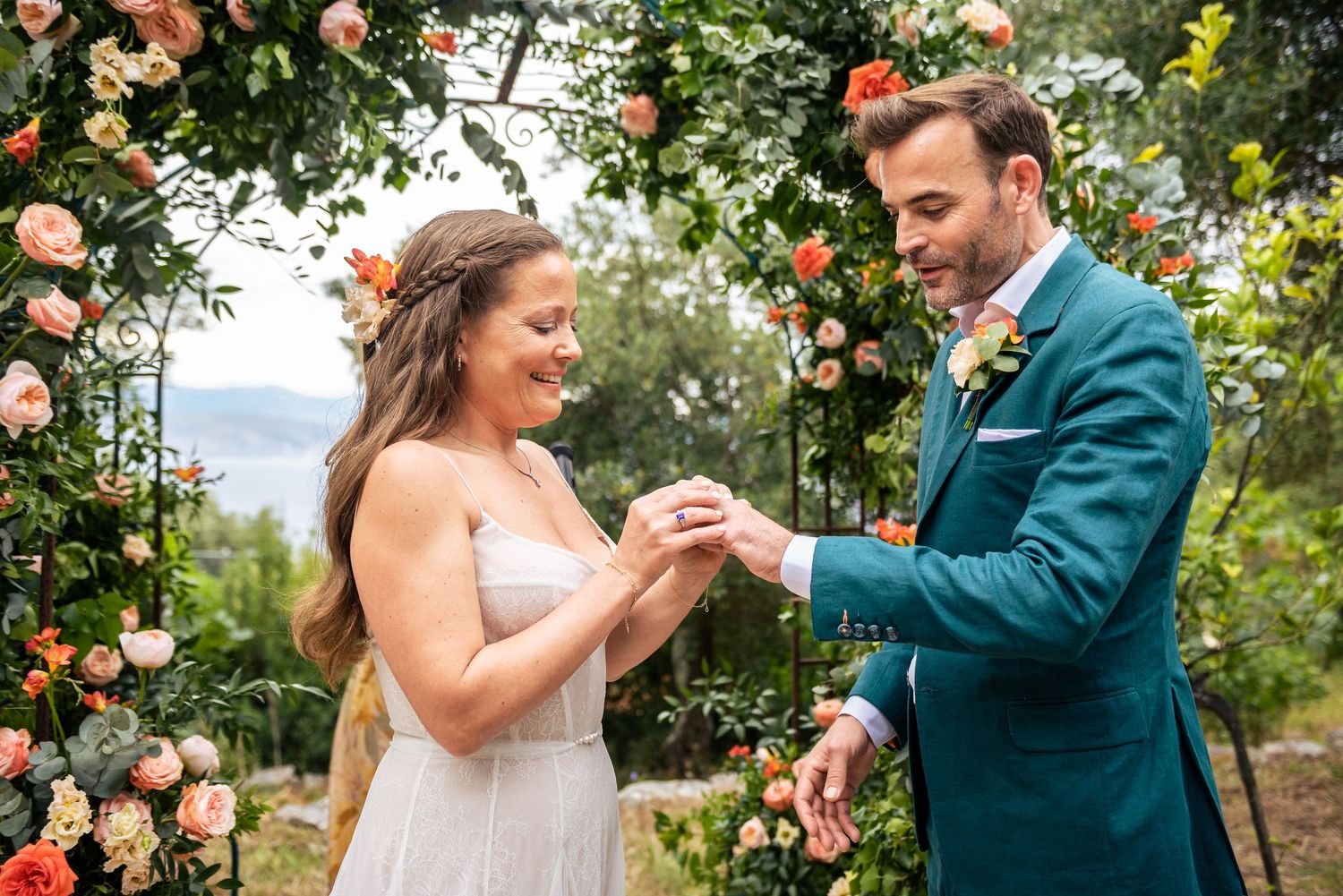 Intimate wedding ceremony moment in a garden setting with coral rose archway.