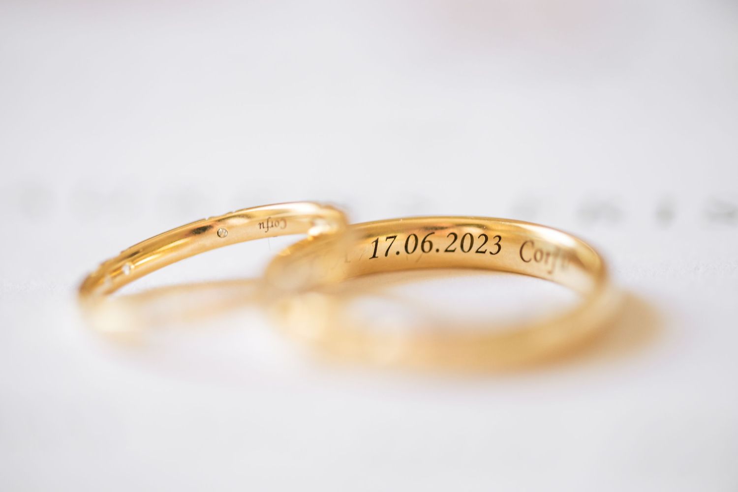 Close-up shots of delicate gold wedding rings with an engraved date.
