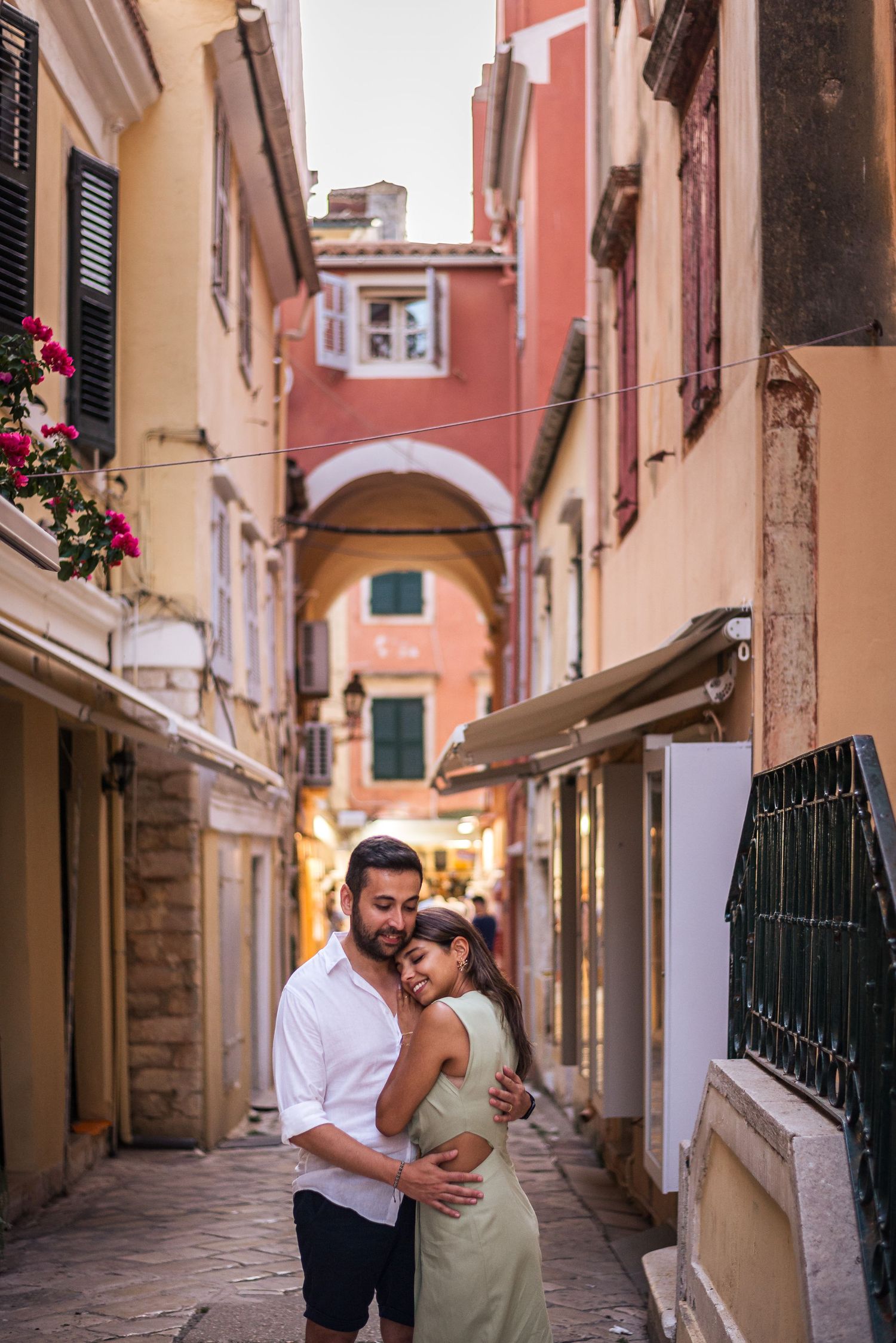 A romantic moment in a narrow Italian alley with pink buildings and an arched passageway overhead.