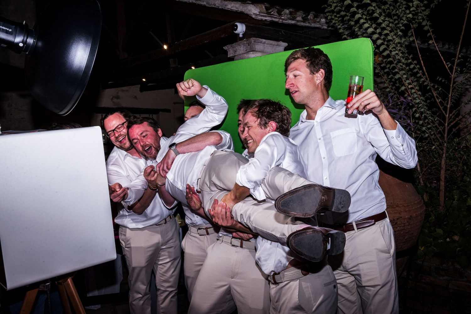 Groomsmen in light colored suits performing a synchronized dance routine at a wedding reception.