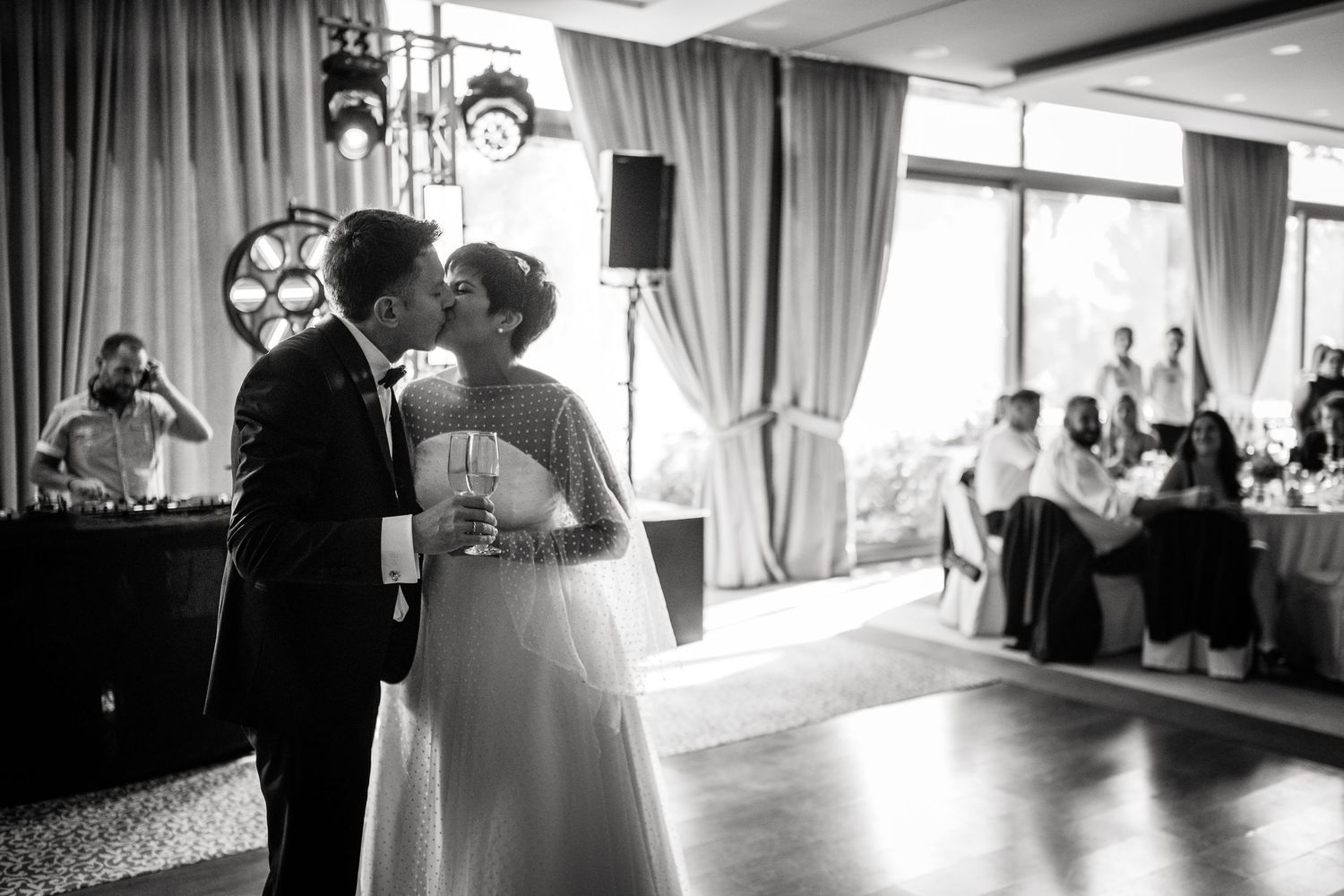 Elegant wedding venue with draped curtains and chandeliers during a reception celebration.
