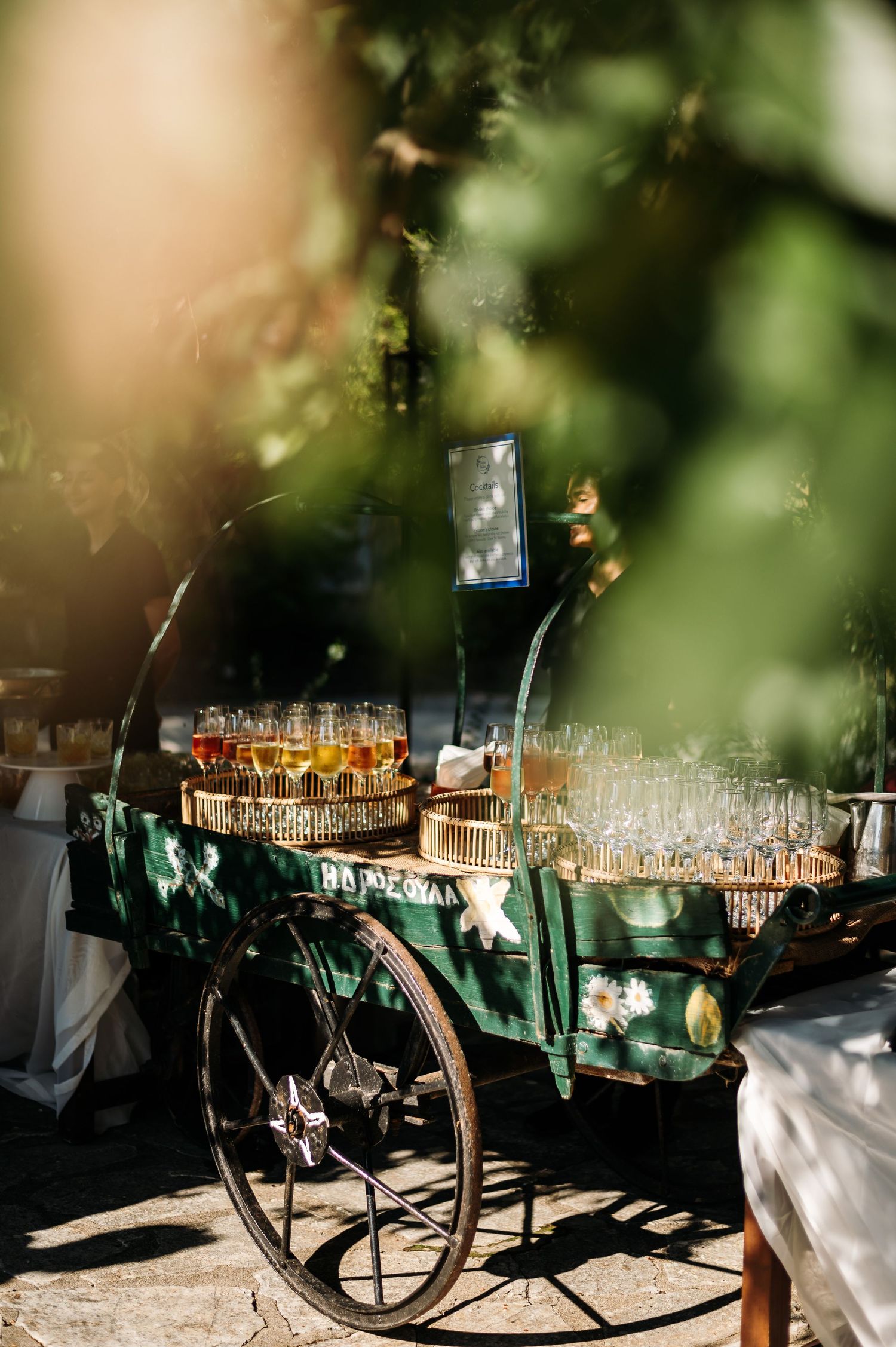 Vintage cart decorated with champagne glasses and drinks for an outdoor wedding reception.