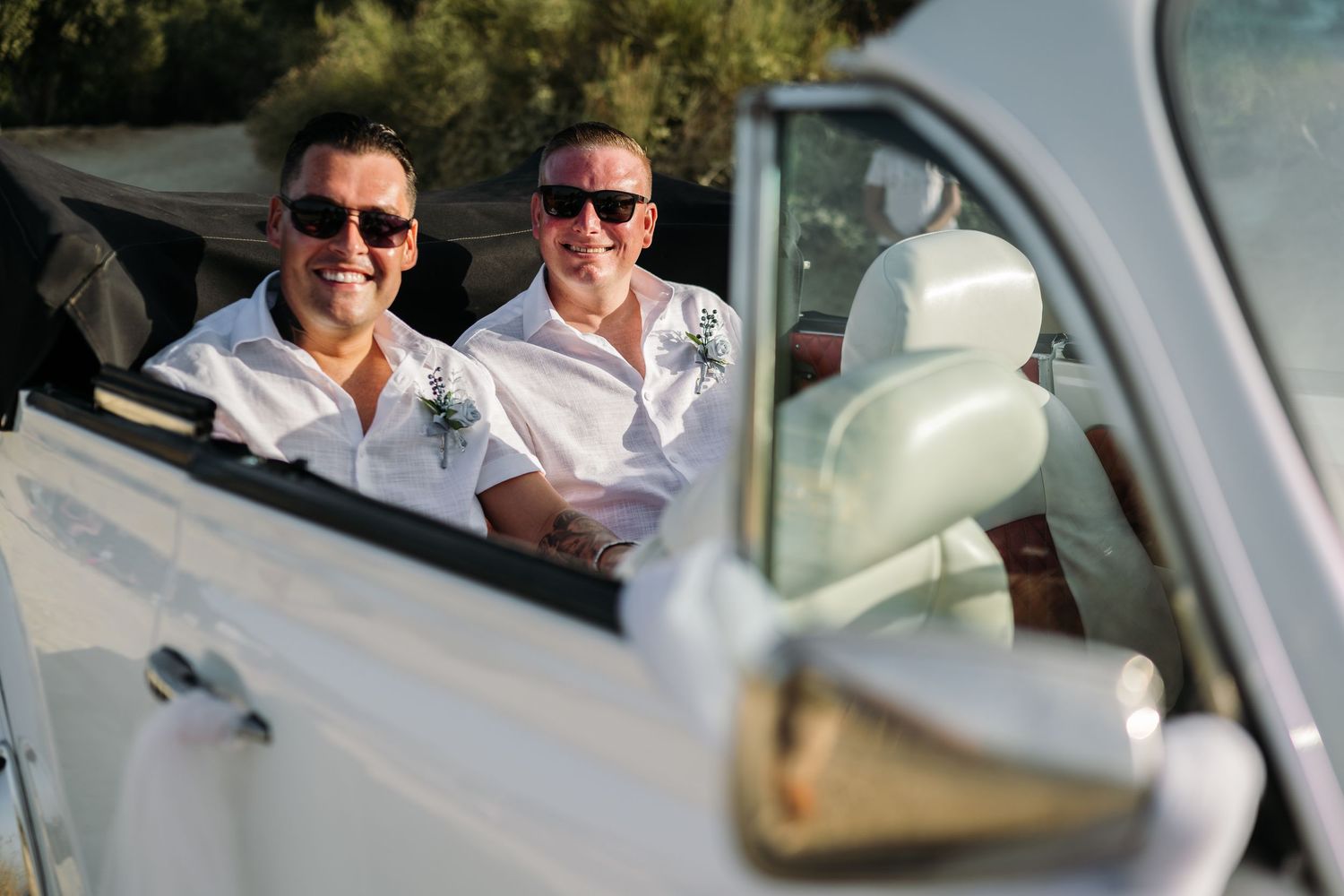 Classic silver vintage car parked with wedding decorations and ocean view in background.