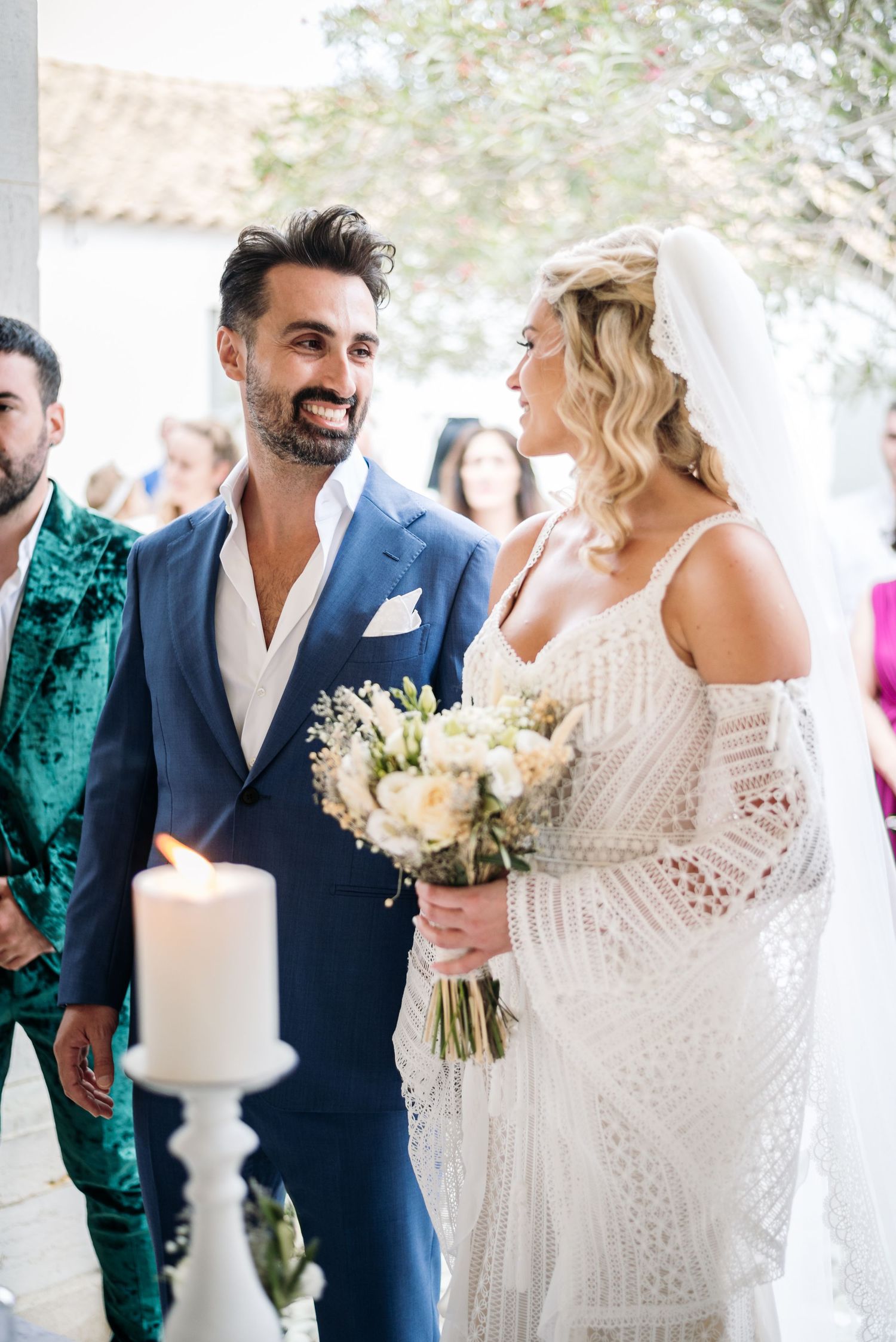 Wedding celebration with elegant white cake and floral arrangements under Mediterranean archway.