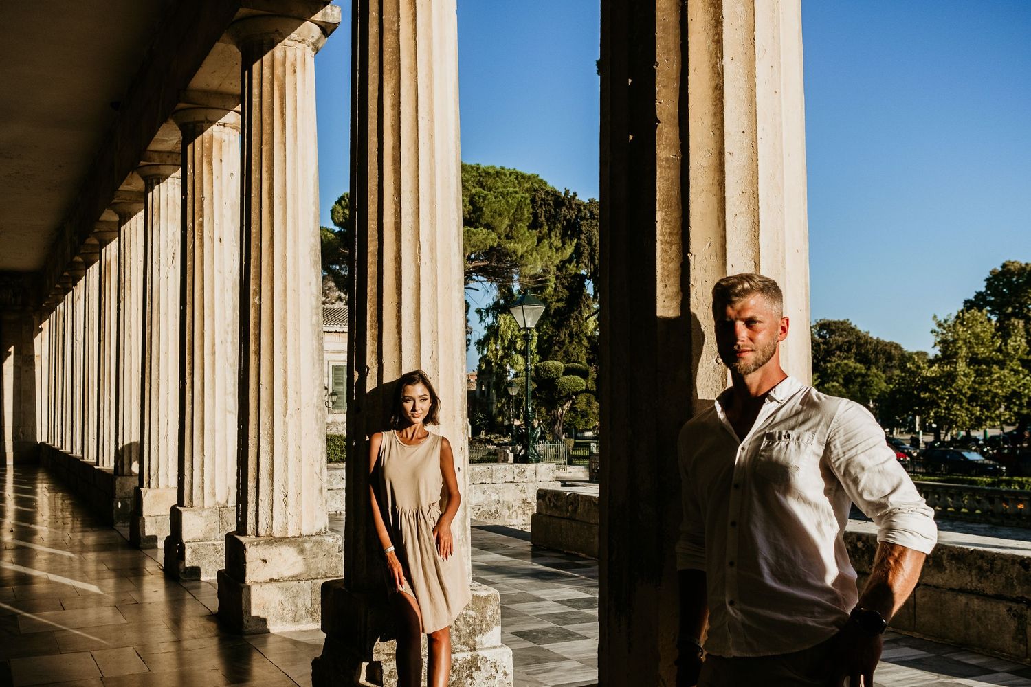 Romantic sequence captured between classical columns with dramatic lighting and shadows.