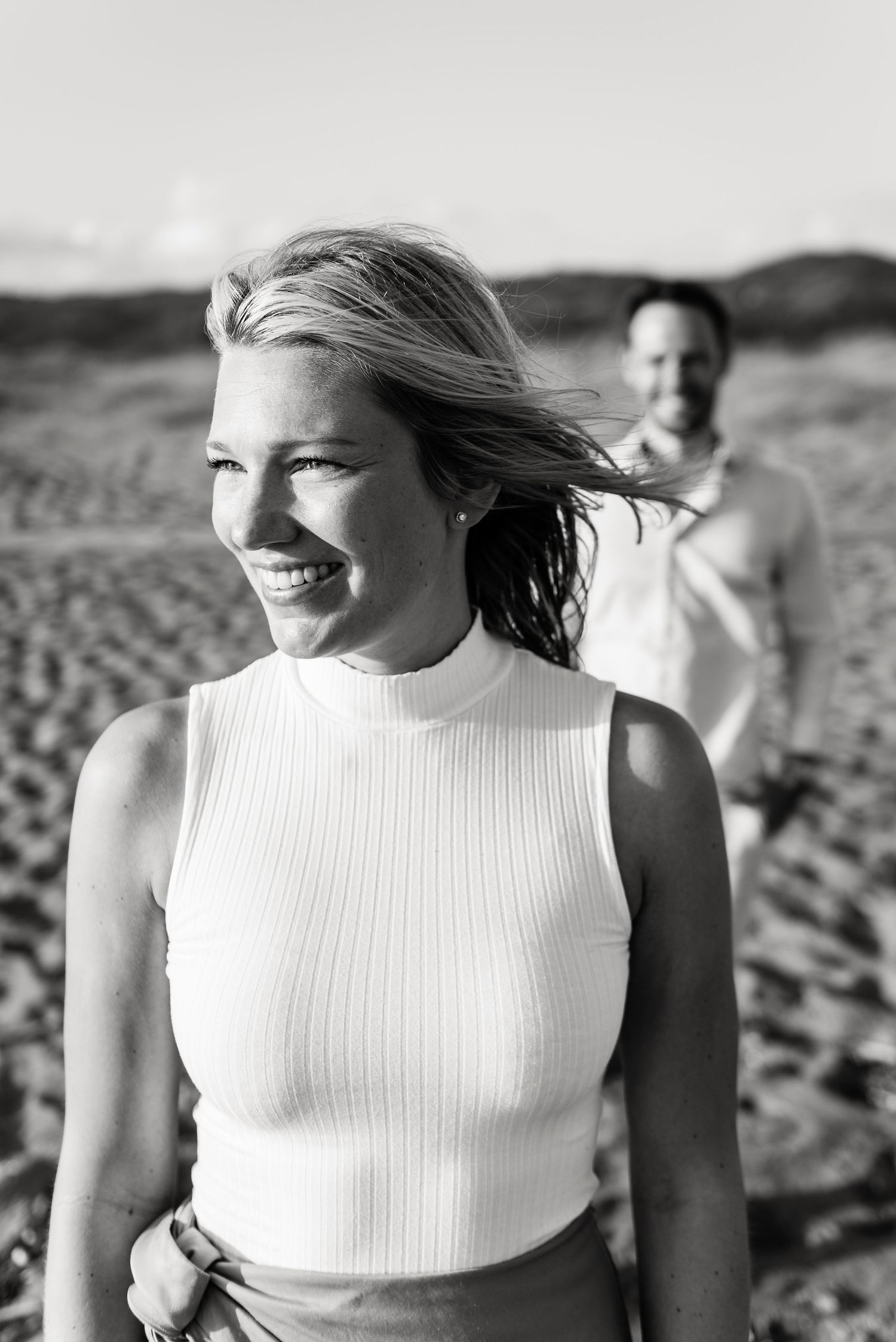 Black and white portrait of a joyful moment on a windy beach.