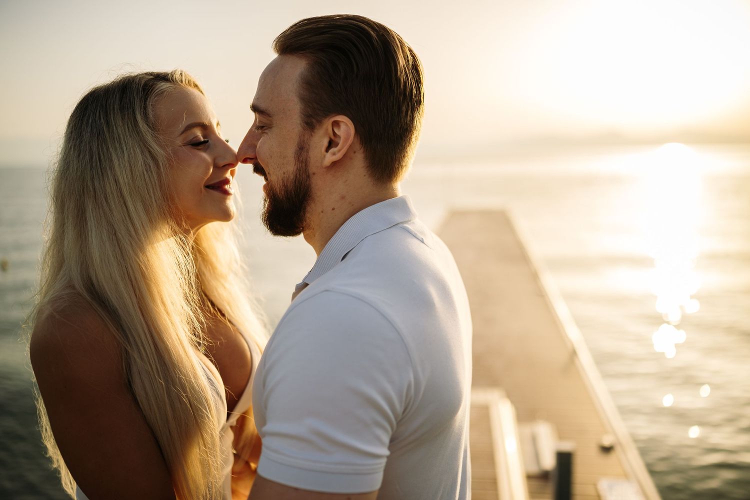 Romantic couple sharing tender moment during golden hour by the ocean.