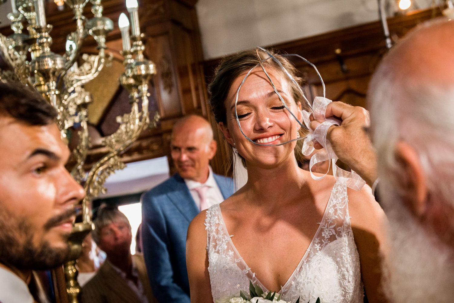 A wedding celebration scene indoors with an ornate chandelier overhead and joyful expressions.