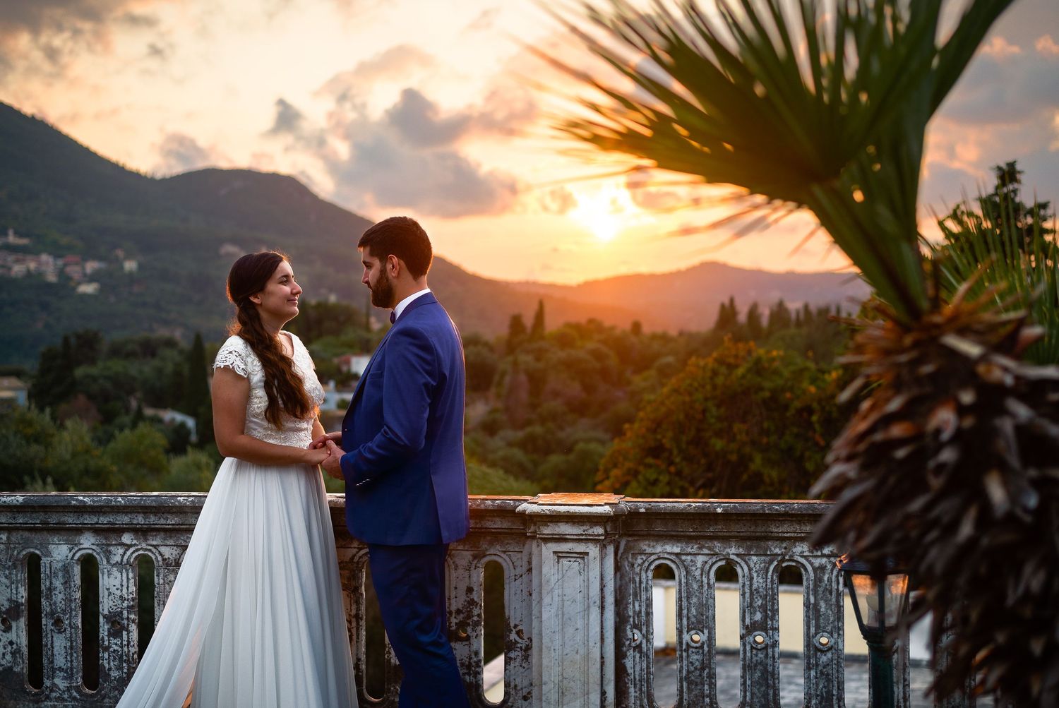 A romantic sunset photoshoot with palm trees and mountain views in the background.