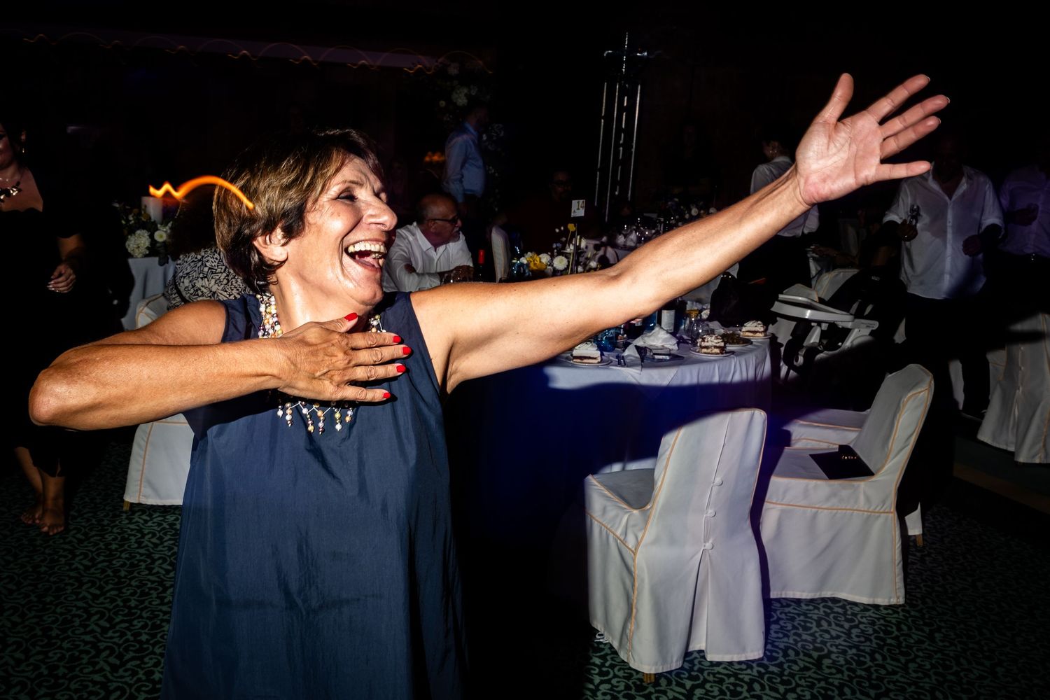Silhouetted dancers with outstretched arms move across a dark dance floor.