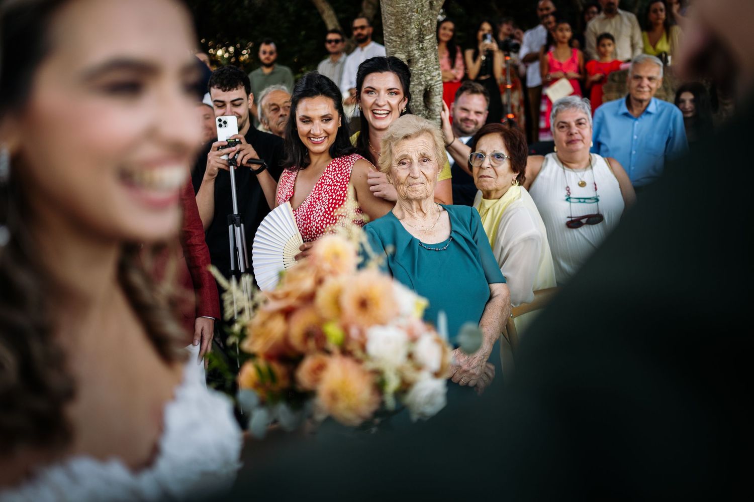 Wedding guests react with joy and emotion during an outdoor ceremony.