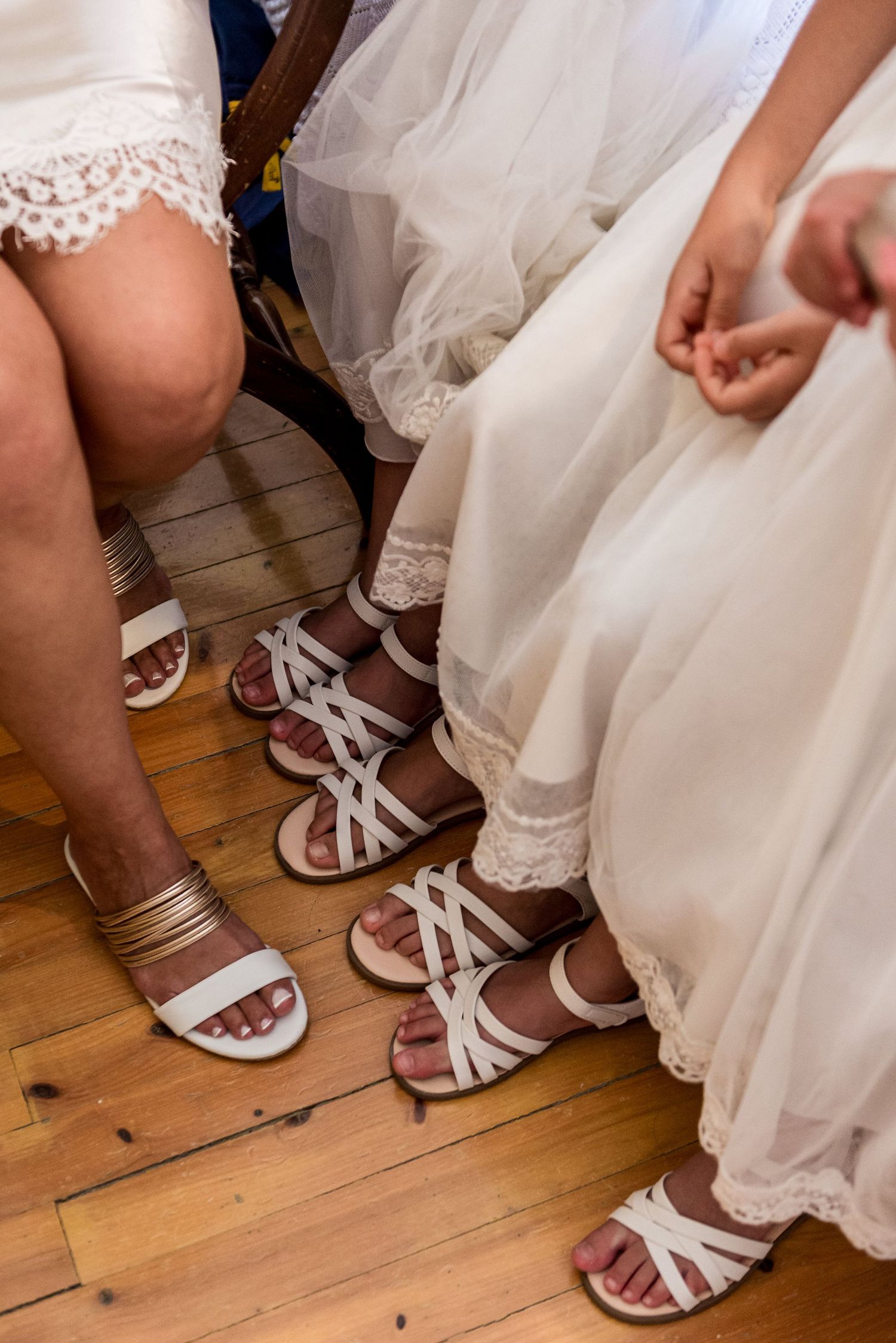 White sandals and lace dress hems visible at floor level during a wedding preparation.