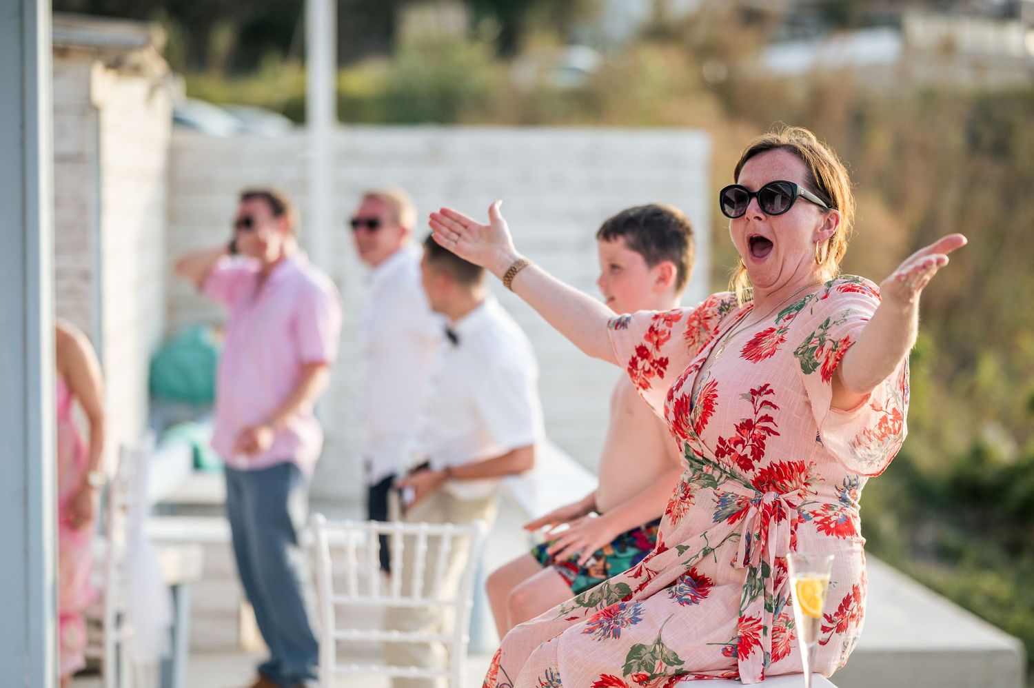 Wedding celebration on a sunny outdoor patio with guests dancing in colorful summer attire.