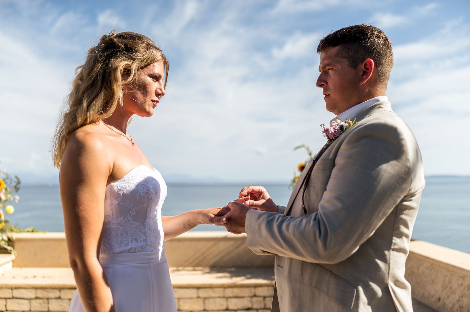 Couple exchanges vows during seaside ceremony with ocean backdrop.