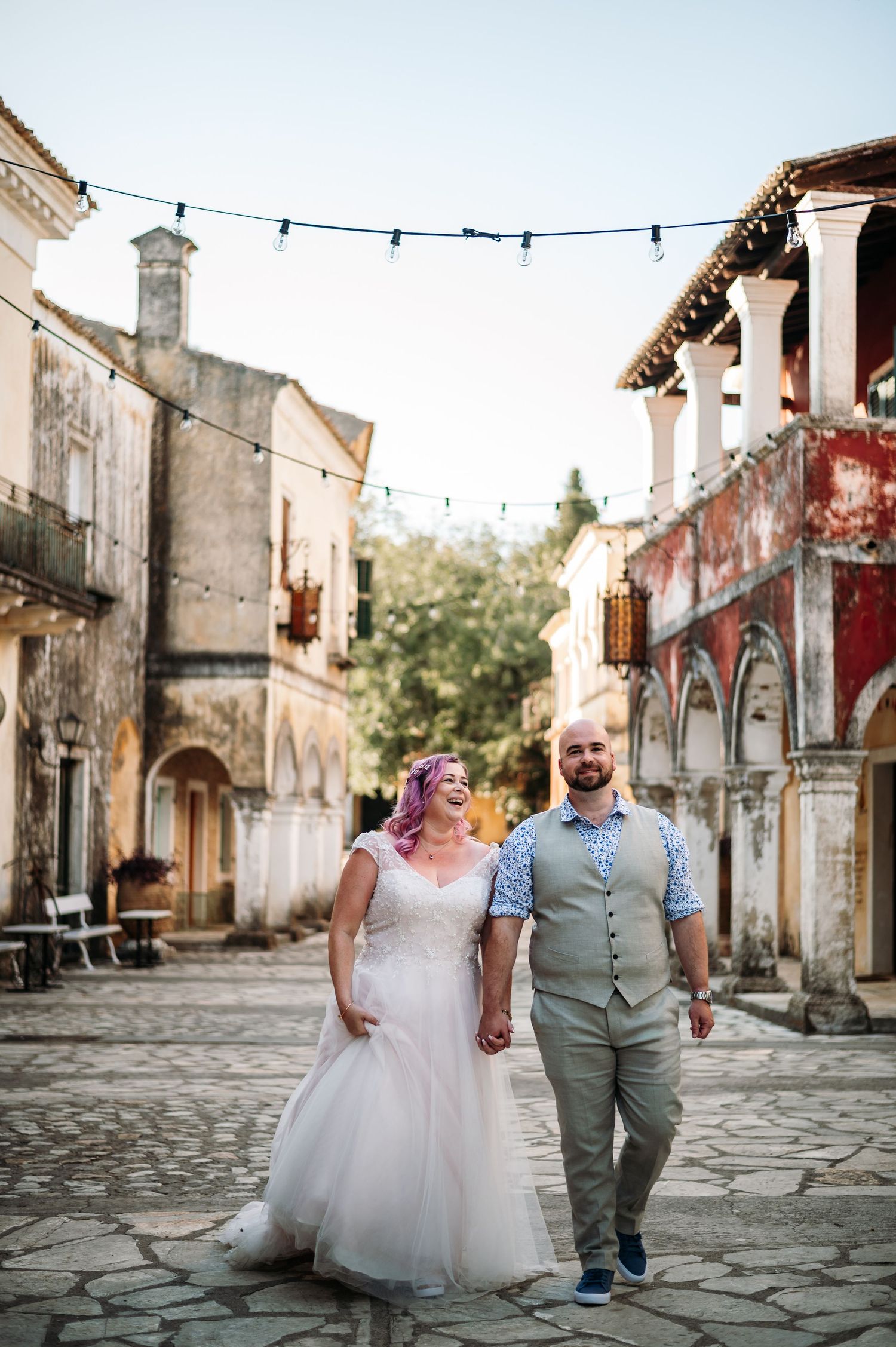 Wedding couple walks hand in hand down a charming cobblestone street.