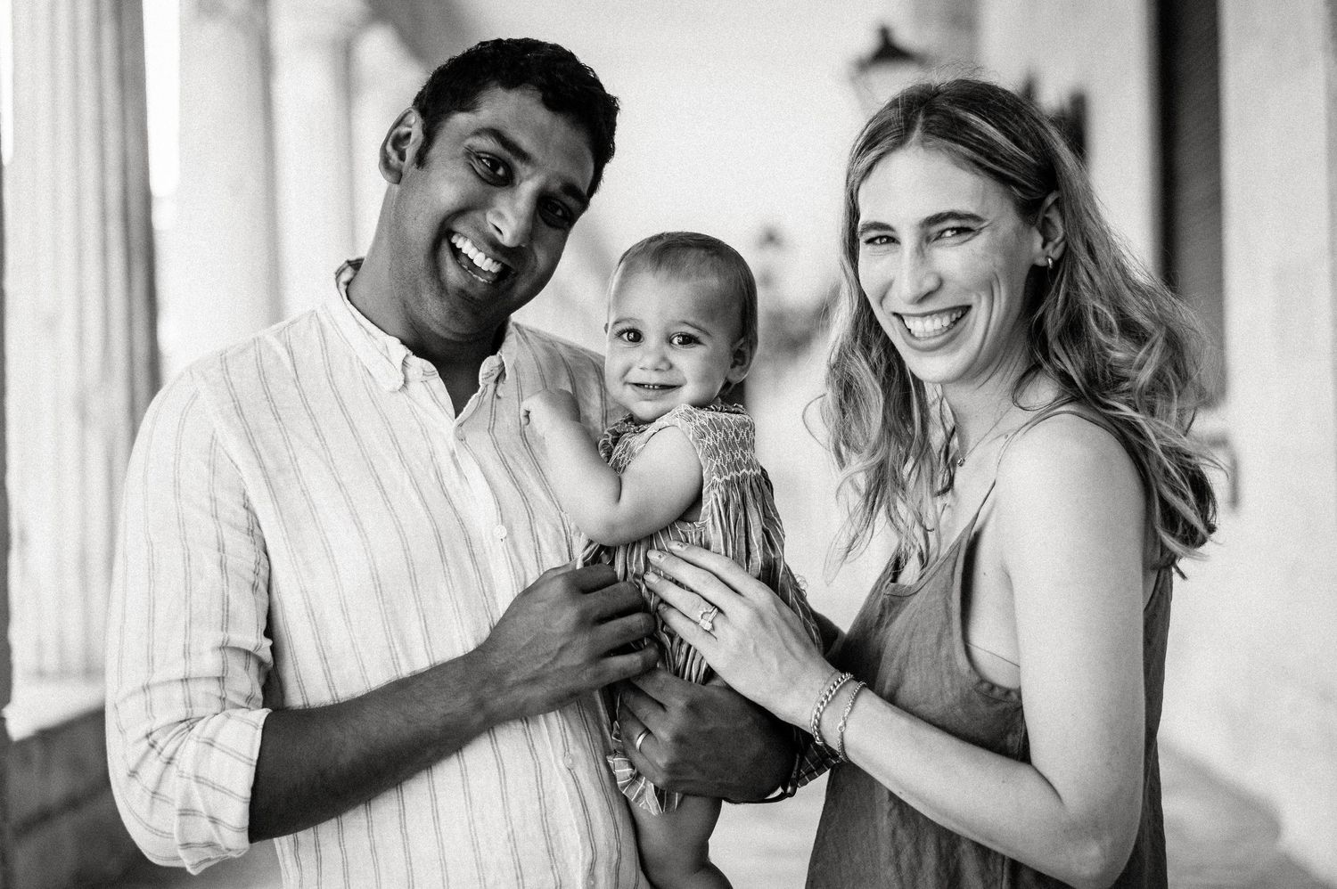 Happy family moment captured in black and white under a columned walkway.