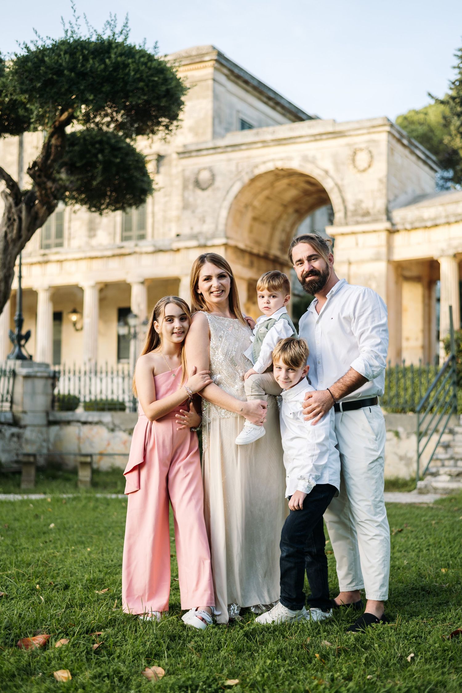 Family portrait in front of a grand historic building with classical architecture.