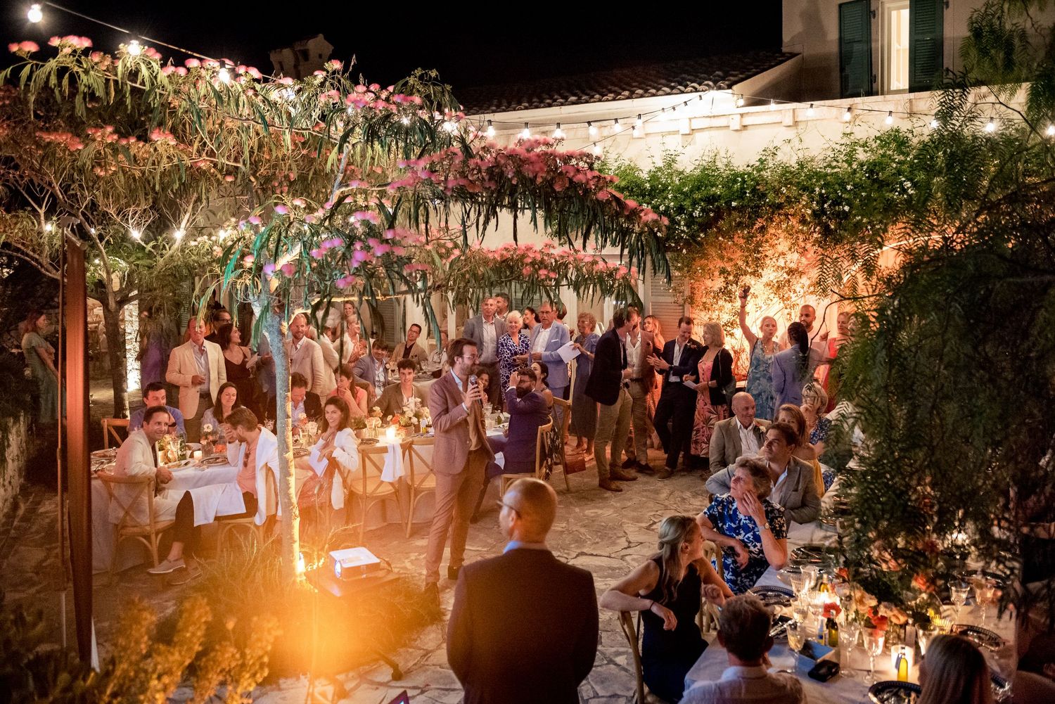 Panoramic view of an outdoor wedding reception venue with string lights and natural surroundings.